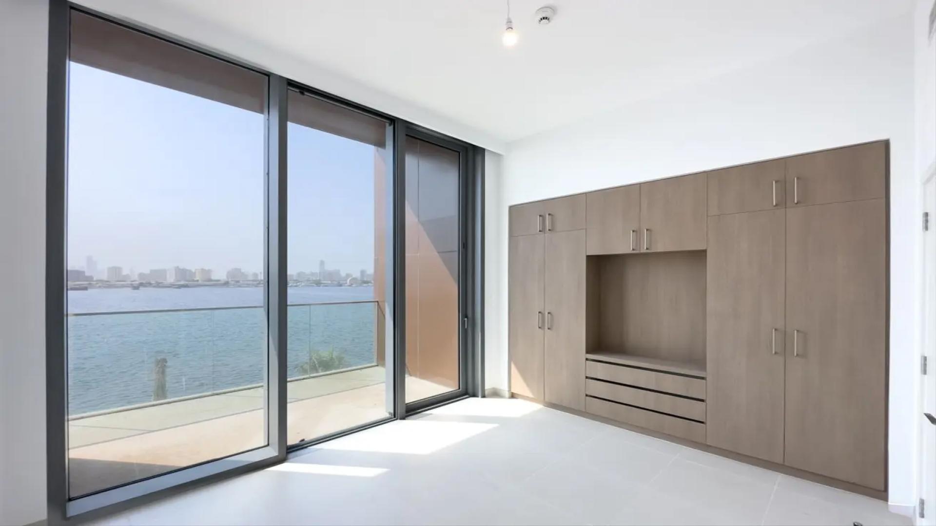 "Bright living area in Dubai Creek Harbour townhouse, featuring large windows and balcony view.",Bright room with built-in wardrobes and waterfront view in The Grand, Dubai Creek Harbour