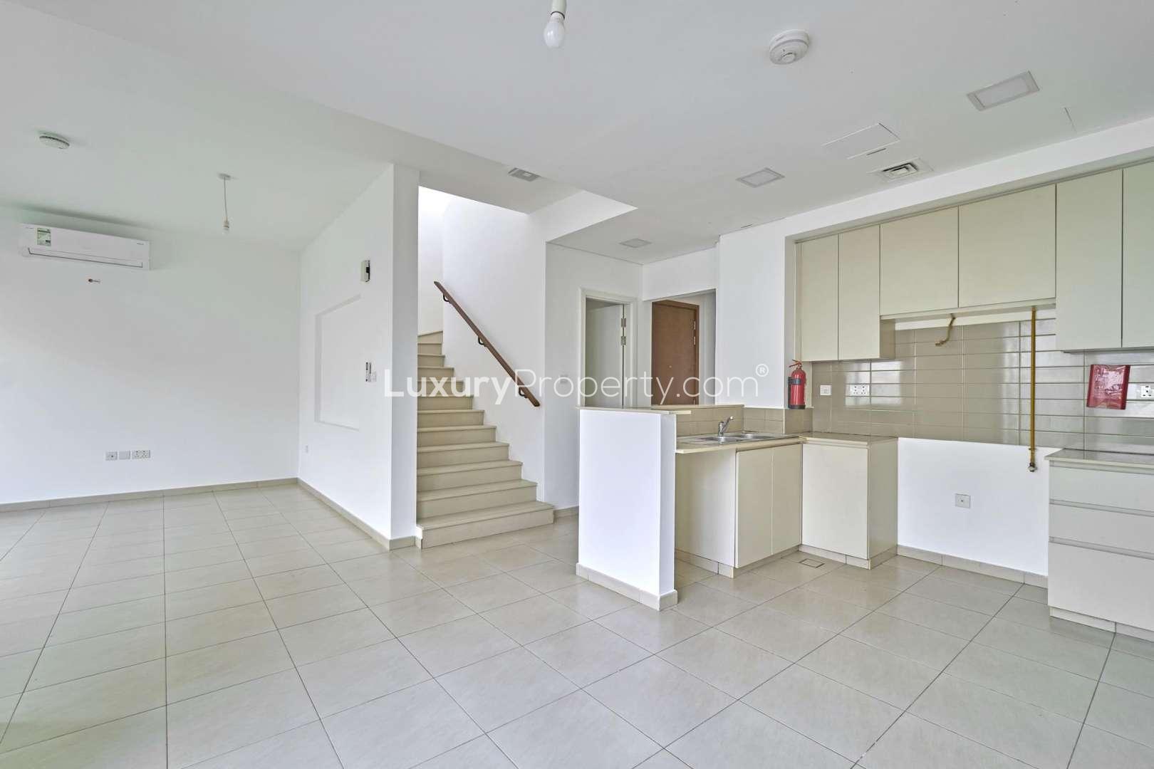 Three-bedroom townhouse exterior in Hayat, Town Square, with parking area and tree view