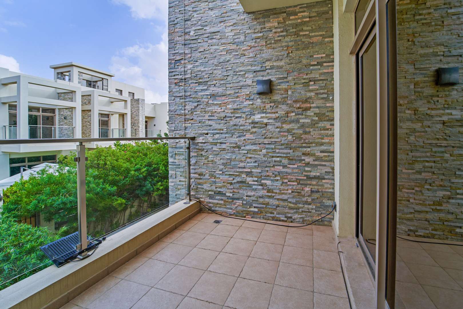 "Charming patio area in 3-bedroom townhouse, Polo Townhouses, Meydan, Dubai, with lush greenery.",Balcony view of spacious townhouse in Meydan Gated Community, Dubai, with stone wall design
