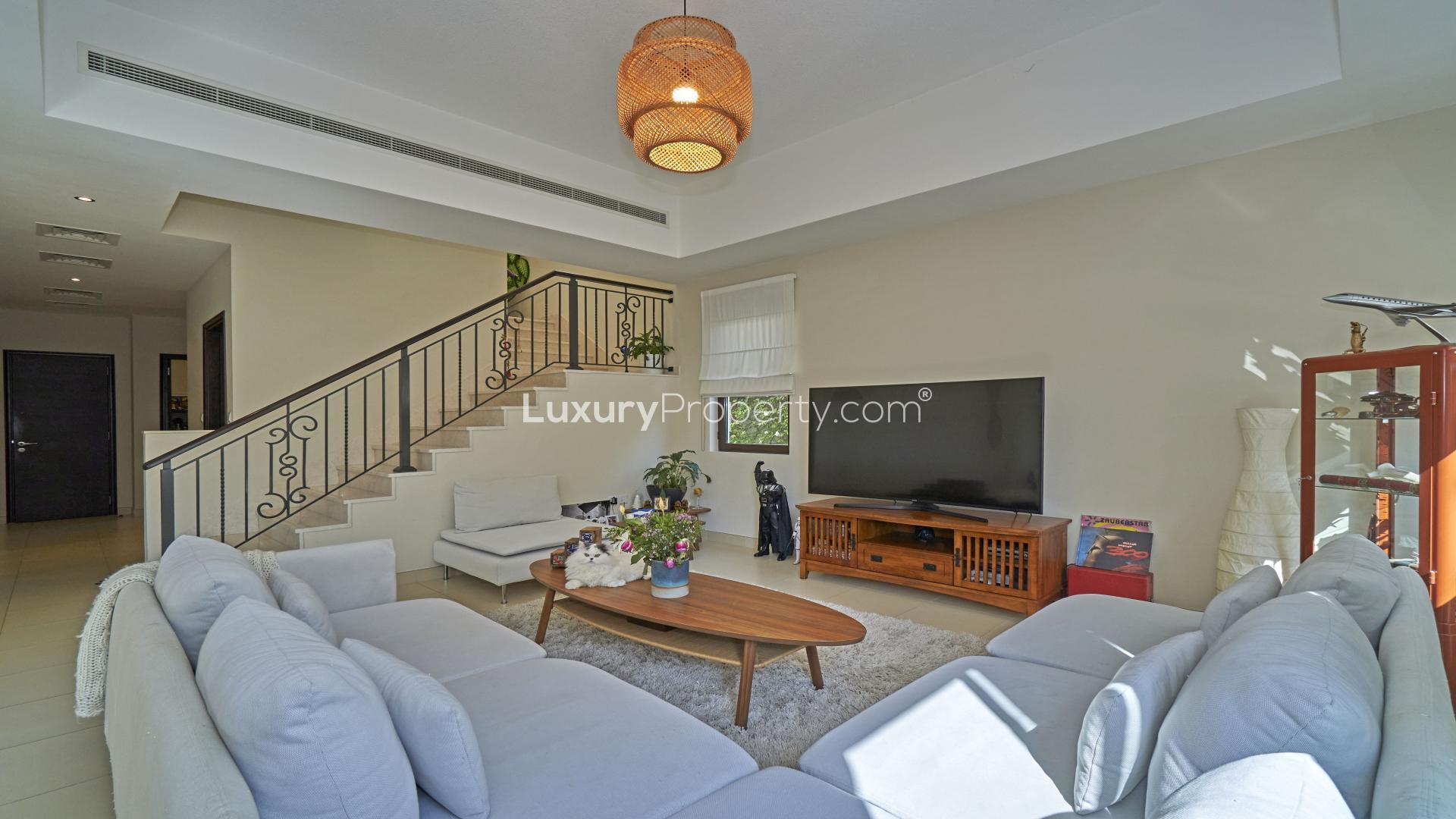 "Front view of spacious 3-bedroom townhouse in Mira, Reem with garden and parking area.",Spacious living room in Mira townhouse with modern decor and natural light