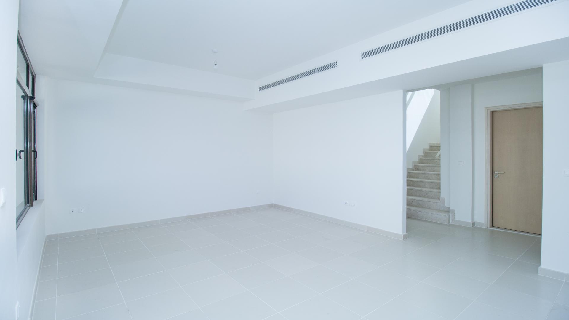 "Modern 3-bedroom townhouse exterior in Mira Oasis, Reem community, Dubai, for rent.",Empty living room in 3-bedroom Mira Oasis townhouse, featuring tiled floors and staircase