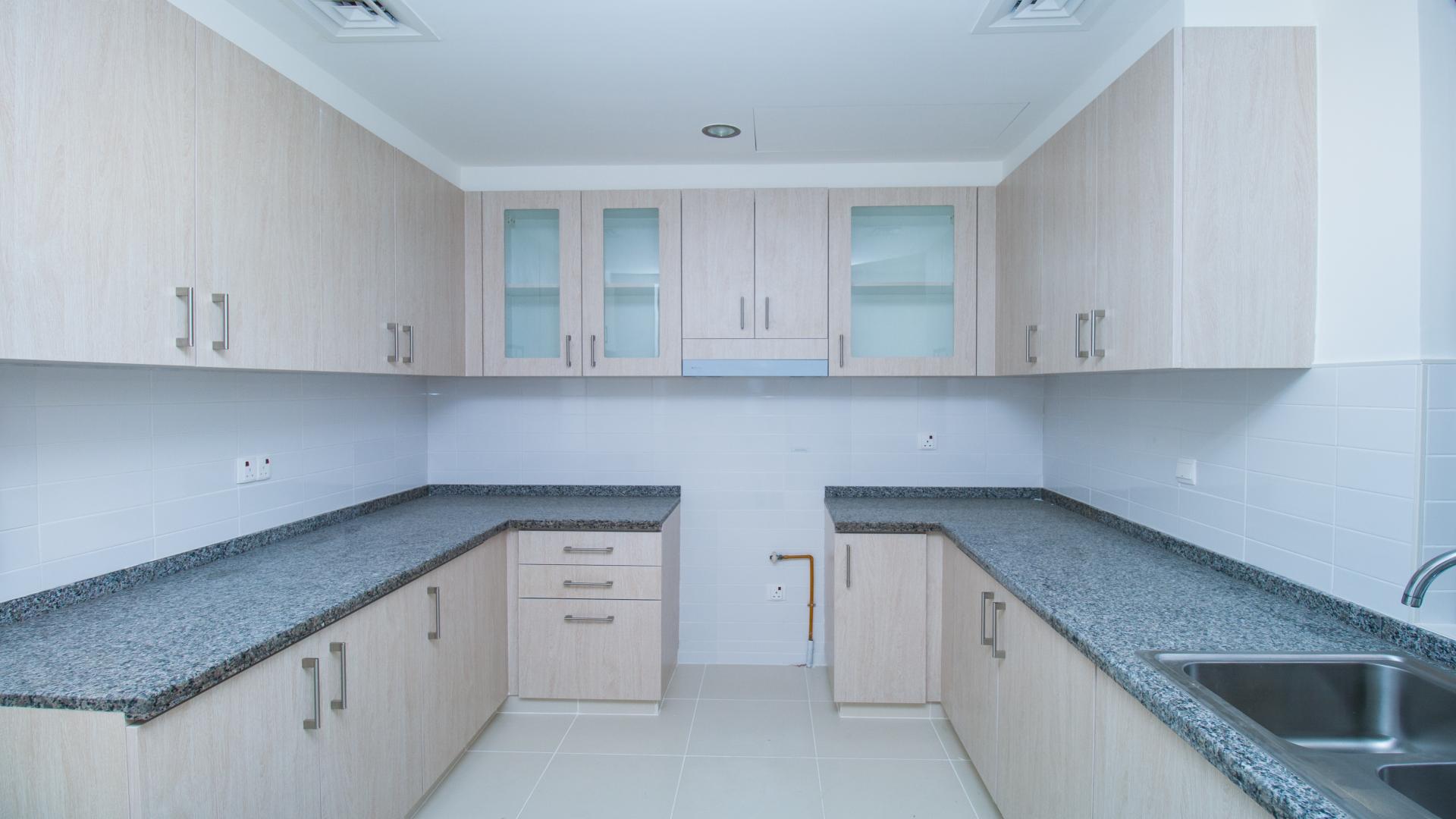 Modern kitchen in 3-bedroom townhouse, Mira Oasis, Dubai, featuring sleek countertops and cabinetry