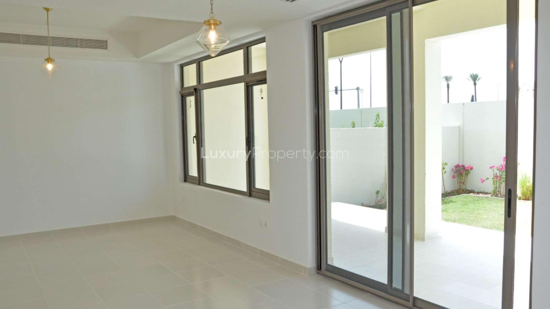 Spacious living area with large windows overlooking garden in Mira Oasis townhouse, Reem