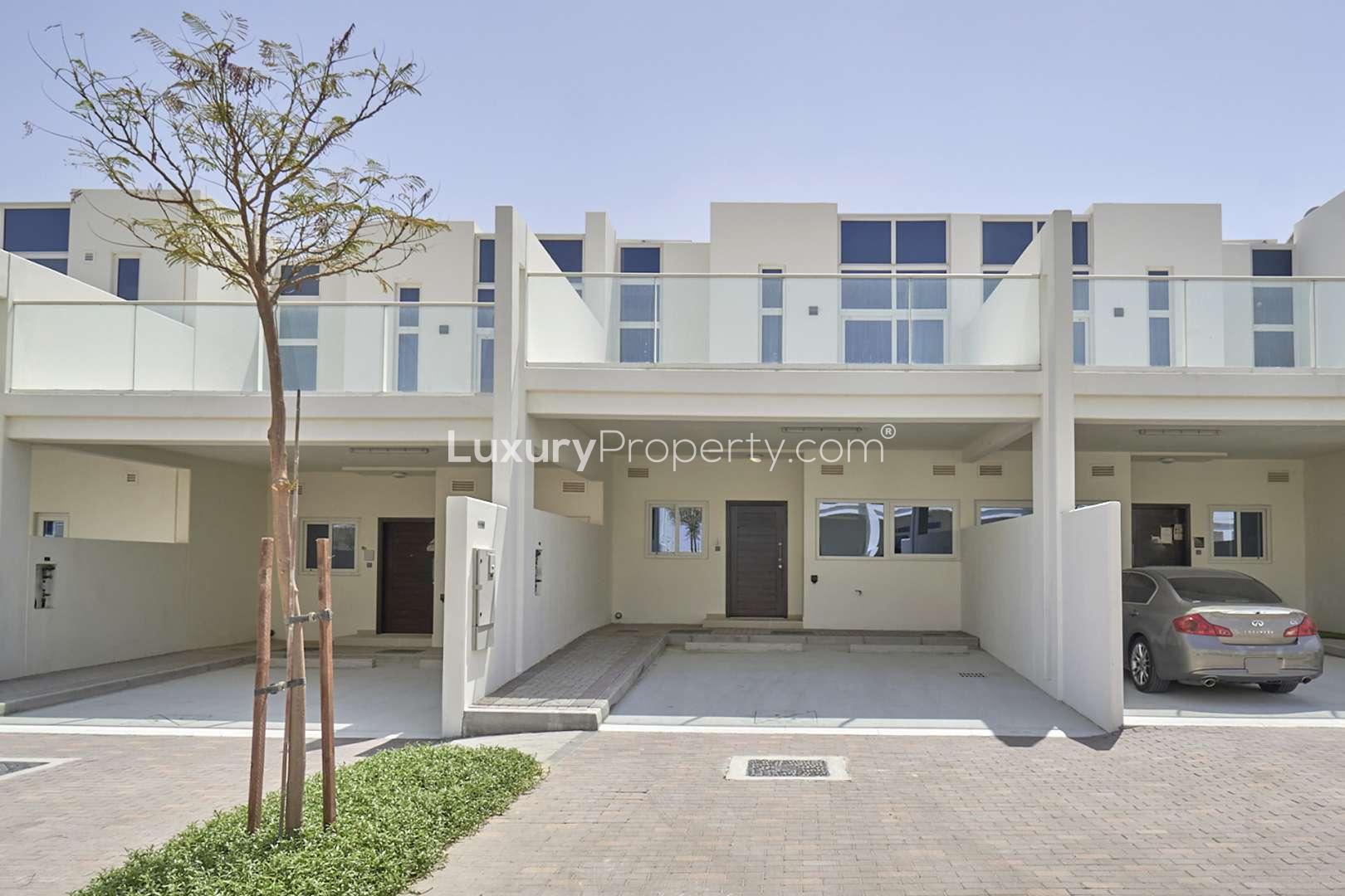 Damac Hills 2 townhouse exterior, street view, modern architecture, green landscaping, sunny day