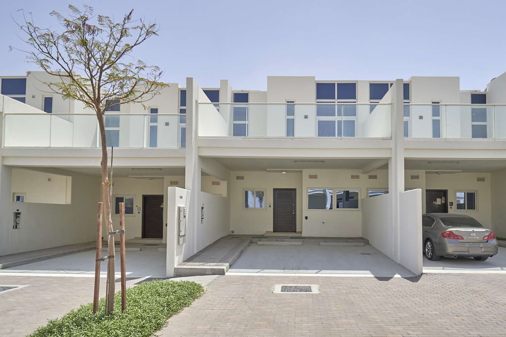 Damac Hills 2 townhouse exterior, street view, modern architecture, green landscaping, sunny day