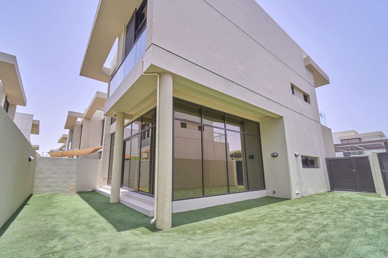 "Bright living room with large windows in Richmond Townhouse, Damac Hills for rent.","Modern townhouse exterior with garden in Damac Hills, Richmond Community, available for rent.",Spacious living room with large windows in Damac Hills townhouse, Richmond Community