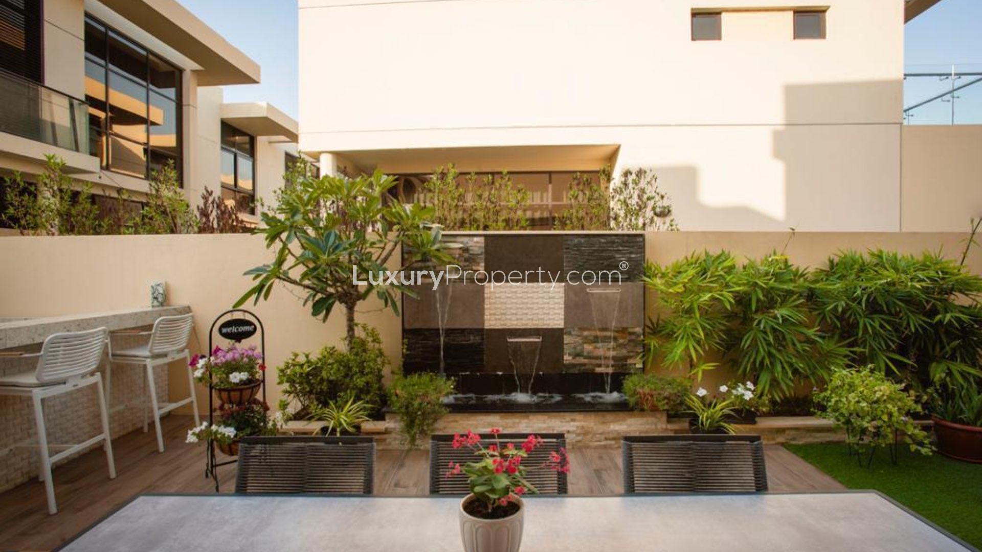 "Upgraded garden patio with BBQ and water feature in Damac Hills townhouse, Rochester community.","Upgraded garden in fully furnished Damac Hills townhouse, Rochester community, with seating and plants.",Outdoor kitchen and garden in upgraded Damac Hills townhouse, Rochester community