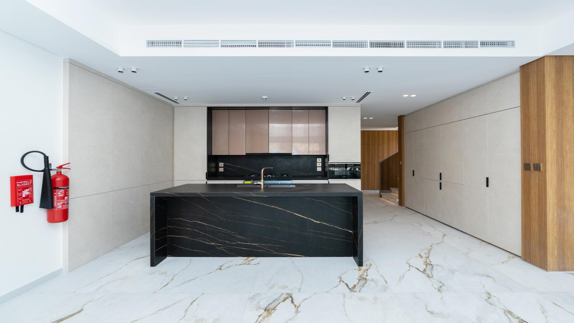 Modern kitchen in Jasmine Lane townhouse, Jumeirah Golf Estates, with marble floors and wooden accents