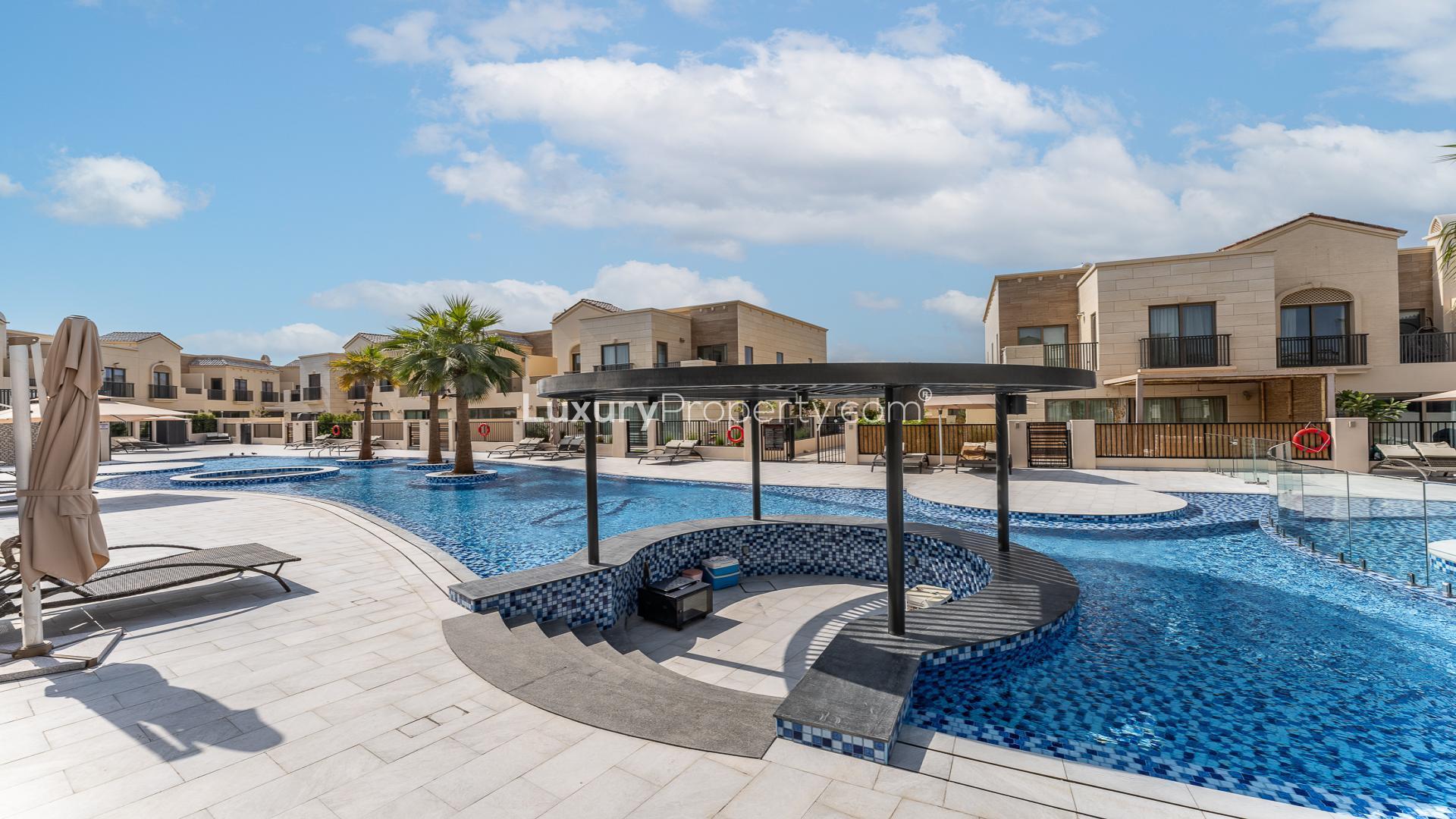 Sunset view of pool and townhouses in Jasmine Lane, Jumeirah Golf Estates