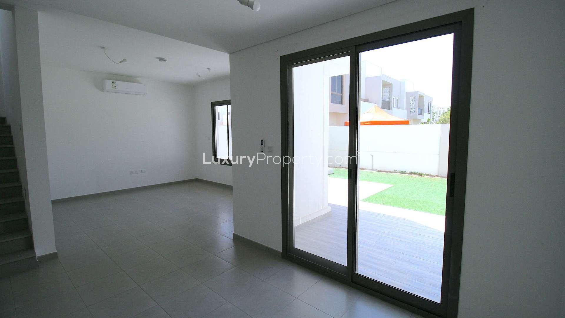Bright living room in Zahra Townhouse, Town Square Dubai, with large windows and tiled floor
