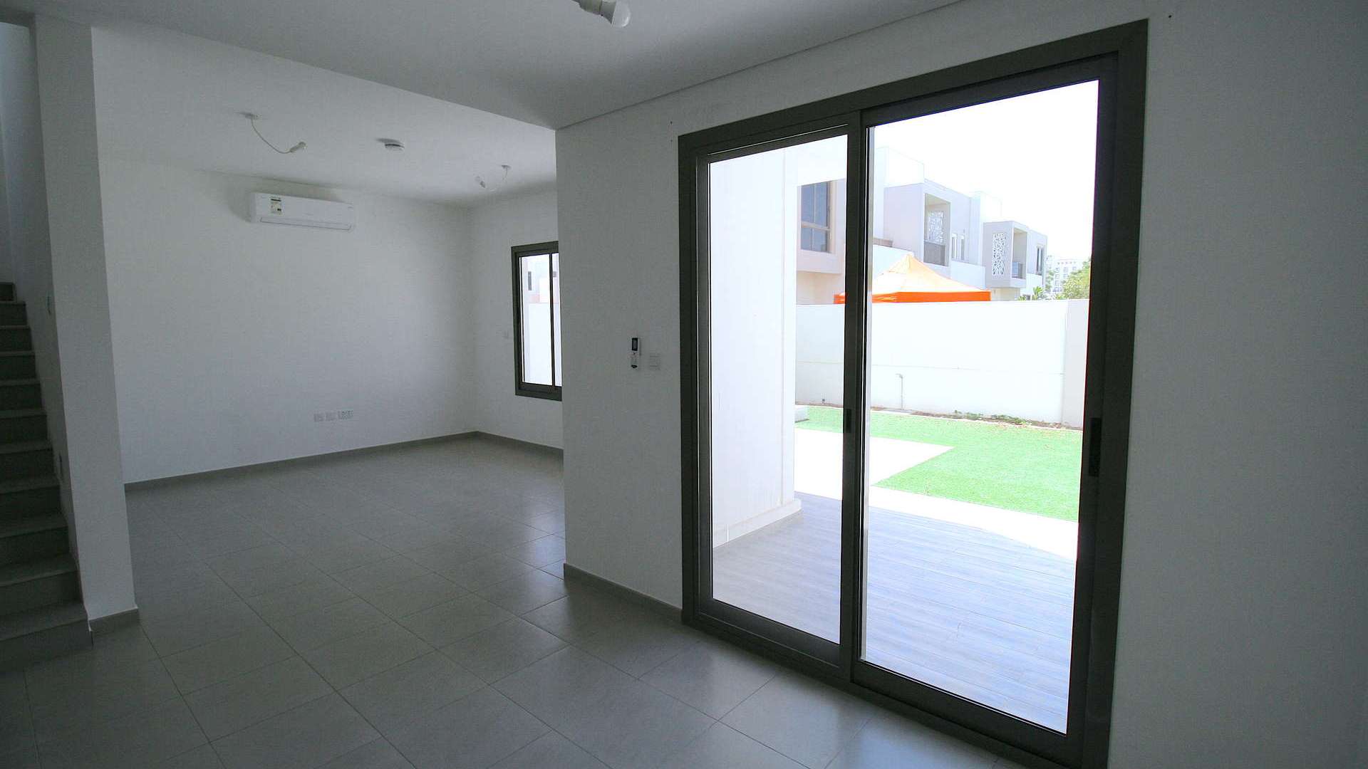 Bright living room in Zahra Townhouse, Town Square Dubai, with large windows and tiled floor