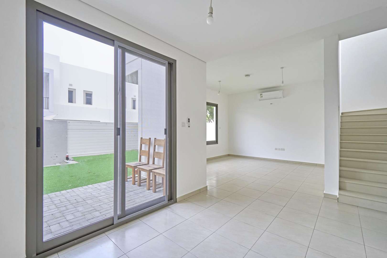 Empty living area in Zahra Townhouse, Town Square, with modern tiled flooring and open layout