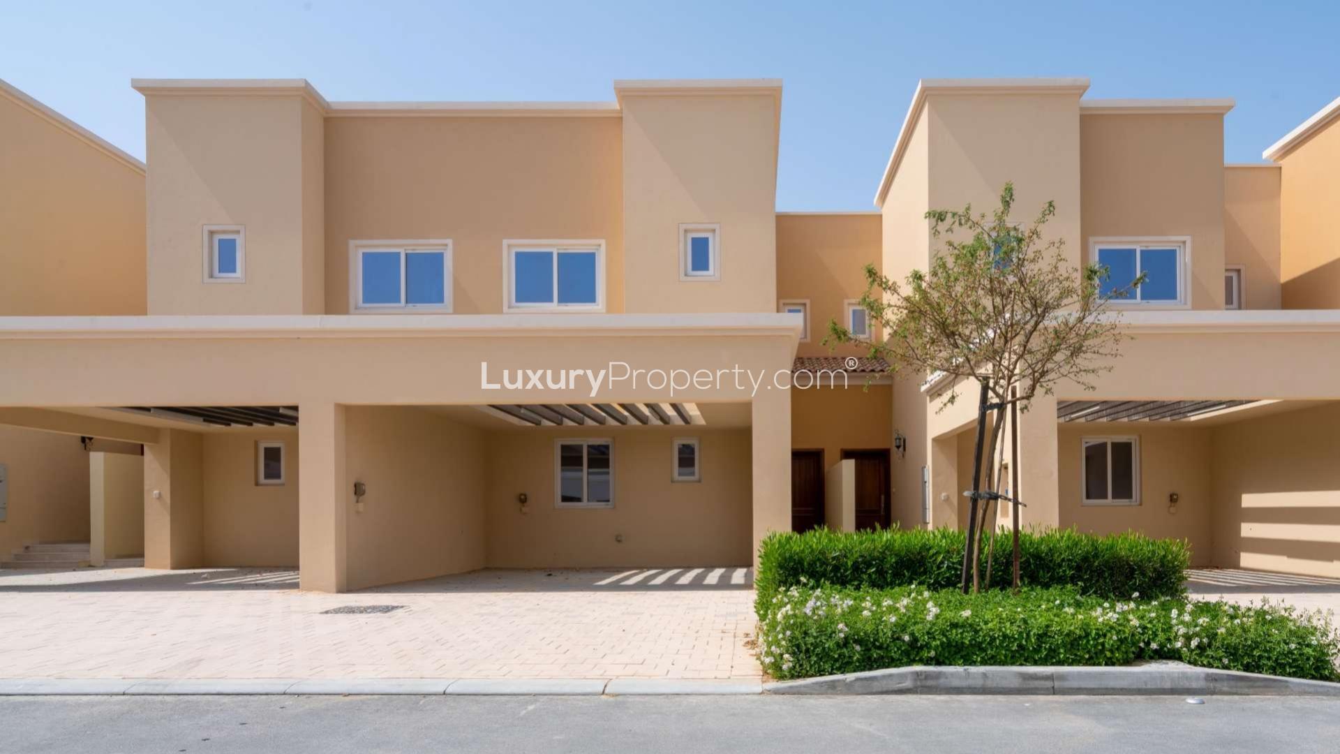 Single row townhouse exterior in Villanova, Dubai Land, with driveway and garden
