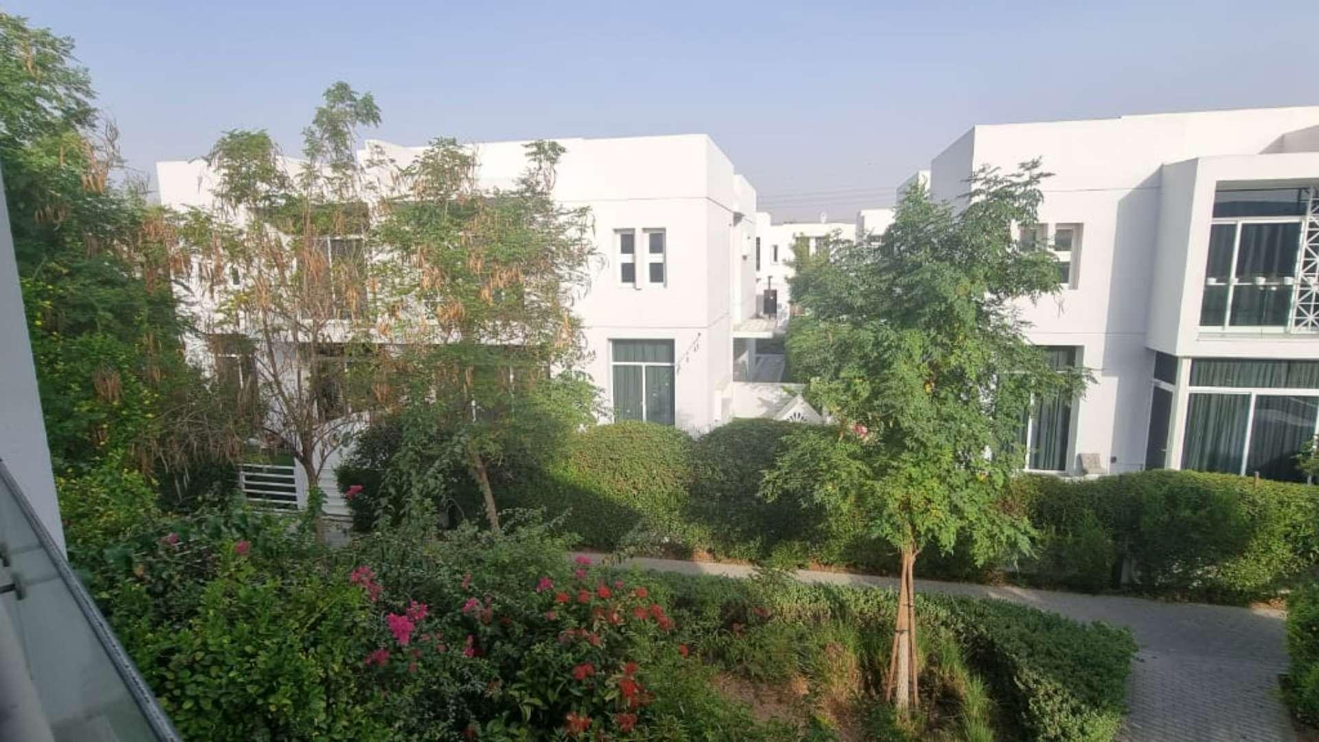 Garden view of Mudon Arabella townhouse with lush greenery and patio area