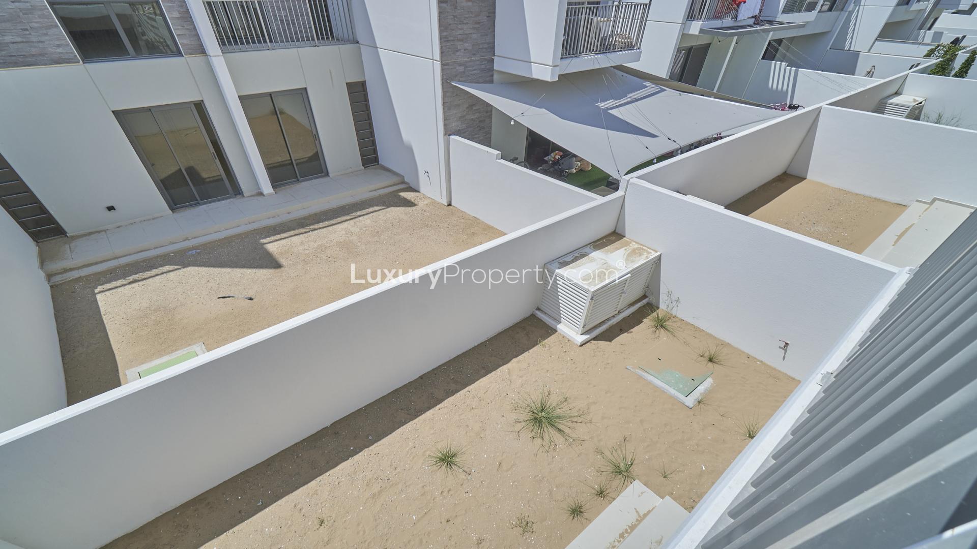 "Balcony view of modern townhouse in Aster, Damac Hills 2, showcasing neighboring units.",Outdoor view of spacious backyard in Trixis townhouse, Damac Hills 2, Akoya community
