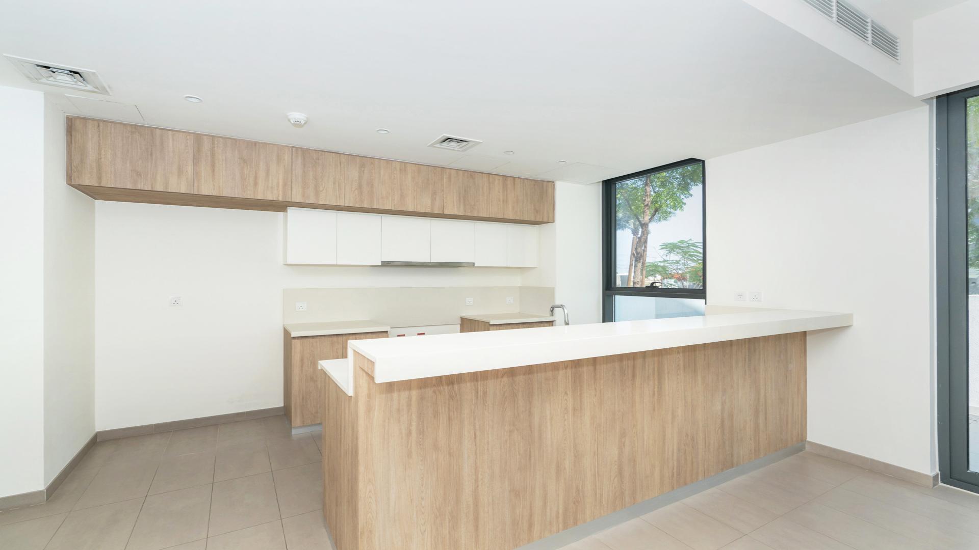 Open-plan living area in Dubai Hills Estate townhouse, featuring modern kitchen and staircase