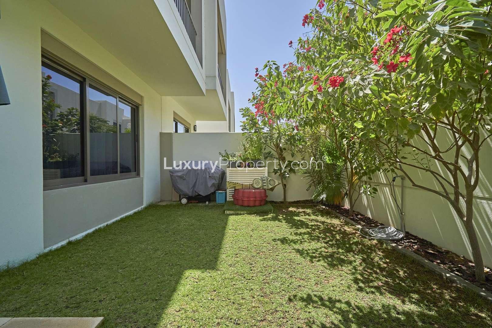 "Modern 3-bedroom townhouse exterior in Hayat, Town Square Dubai, with greenery and driveway.",Private garden of 3-bedroom townhouse for rent in Hayat, Town Square, Dubai