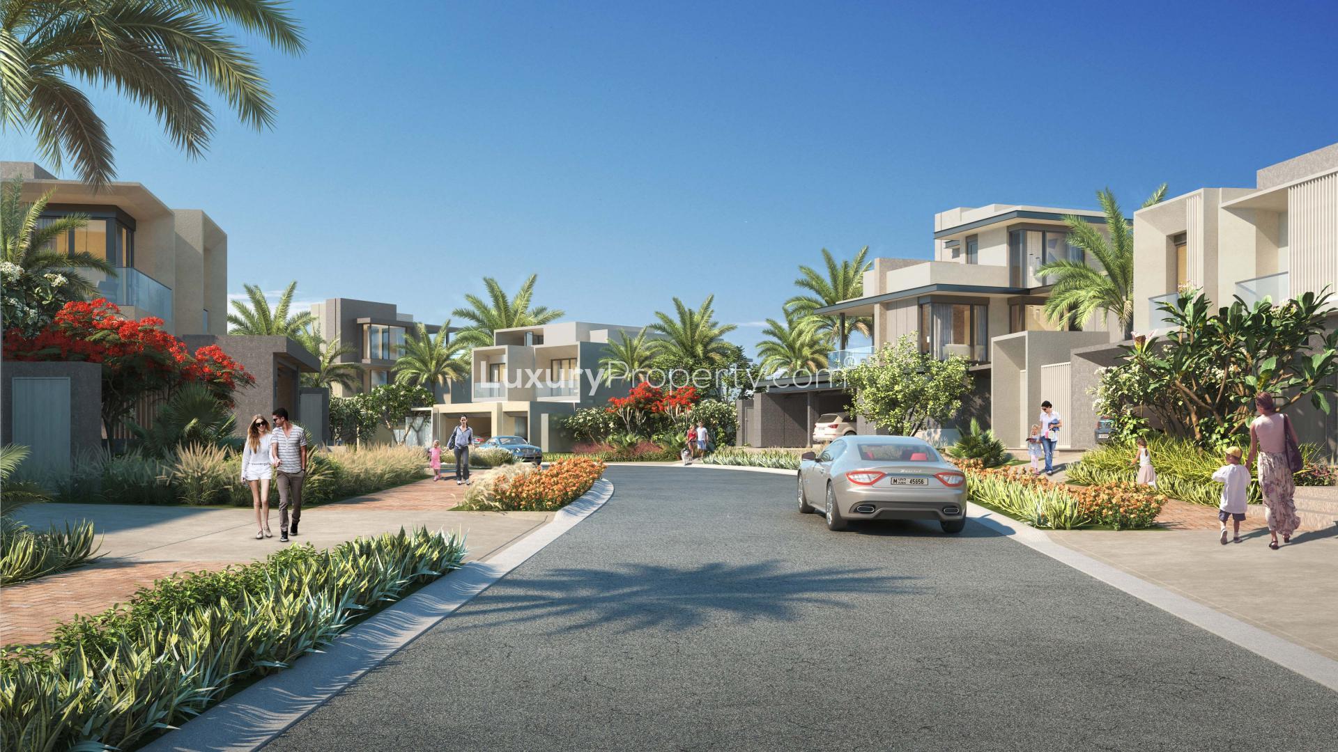 Entrance to Jebel Ali Village townhouse community with lush landscaping and palm trees