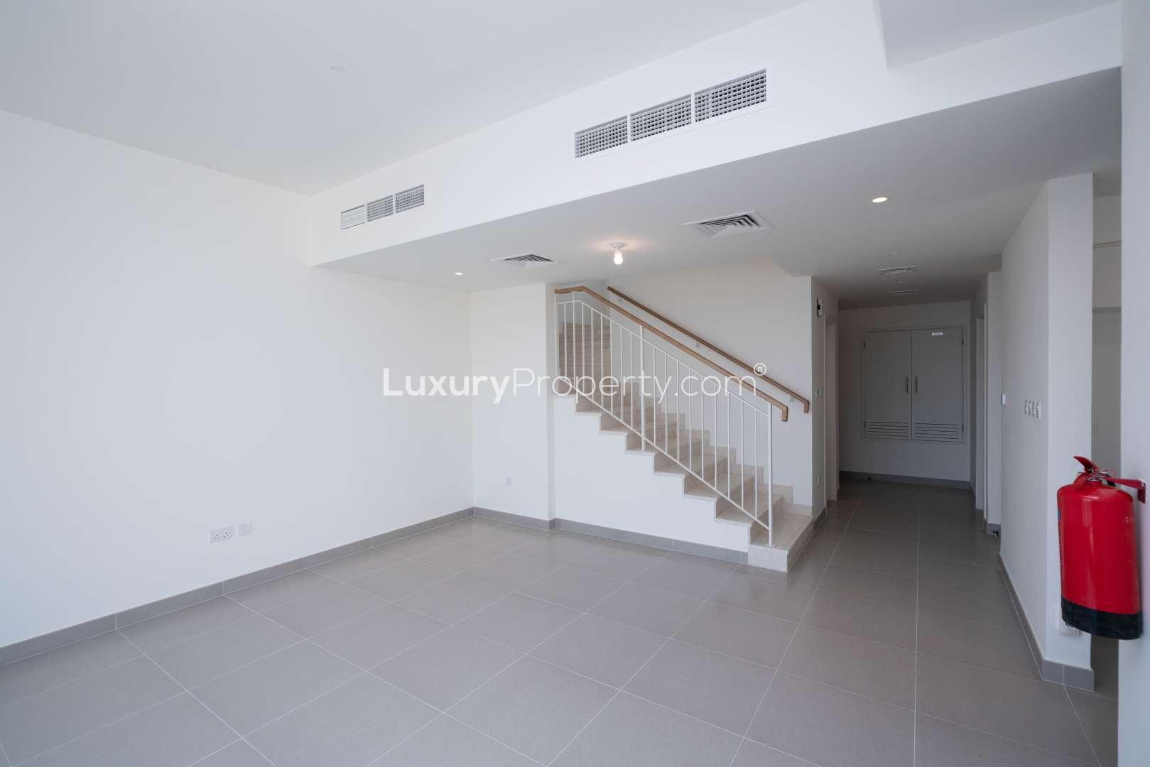 Modern living area in 3-bedroom townhouse, Maple, Dubai Hills Estate, with staircase and large window