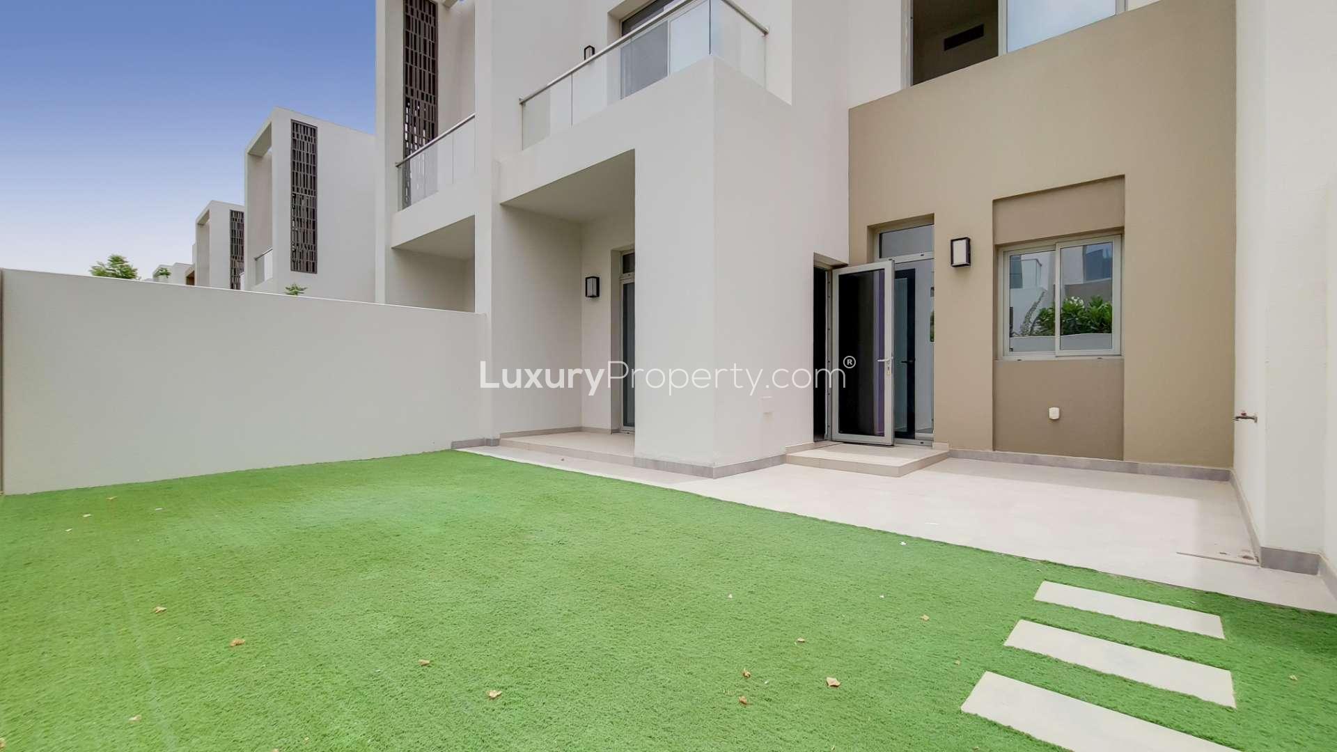 Stunning 3-bedroom townhouse exterior with green lawn in Reem