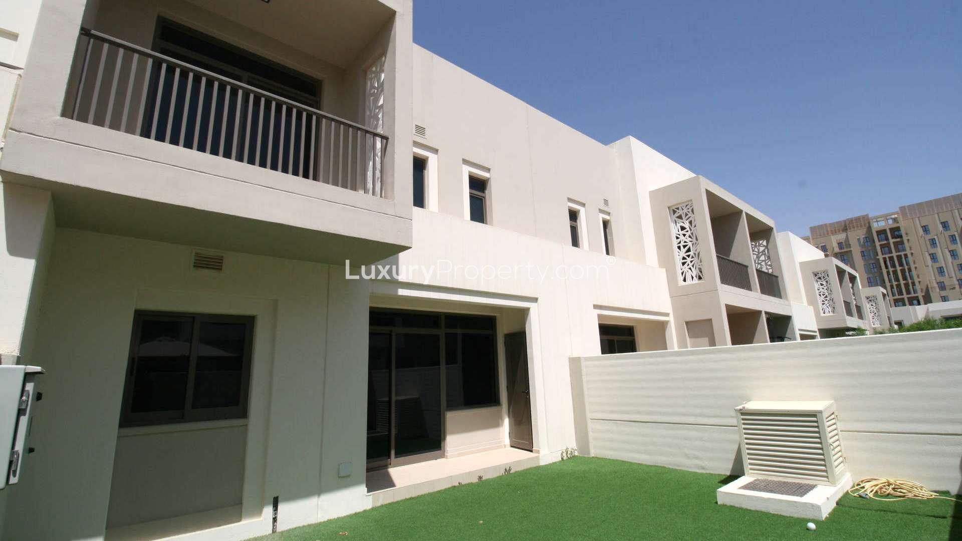 Outdoor sports court near Zahra Townhouses, Town Square, with basketball hoops and green surface