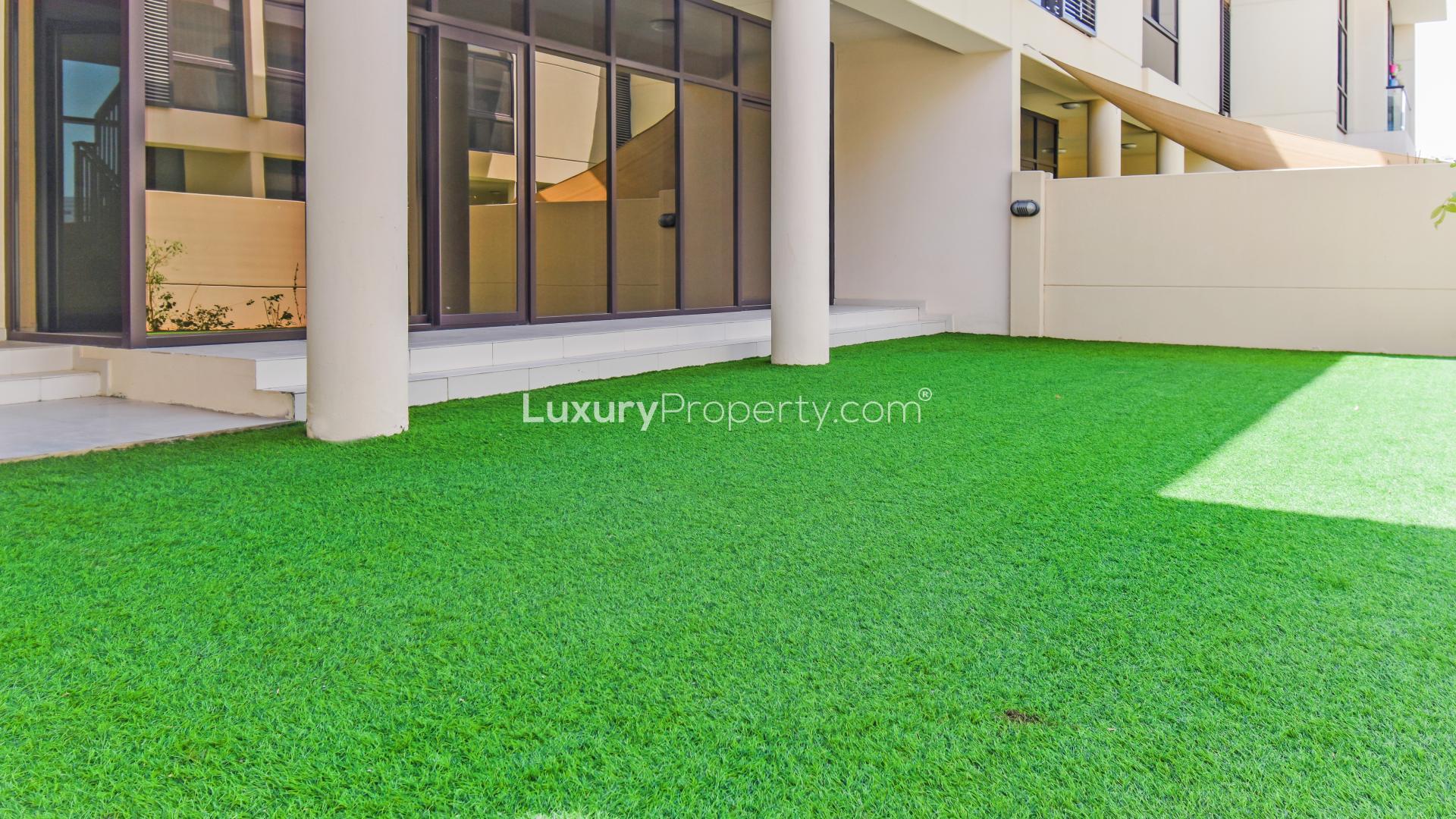Outdoor patio area with green artificial lawn in Akoya Park villa, Damac Hills