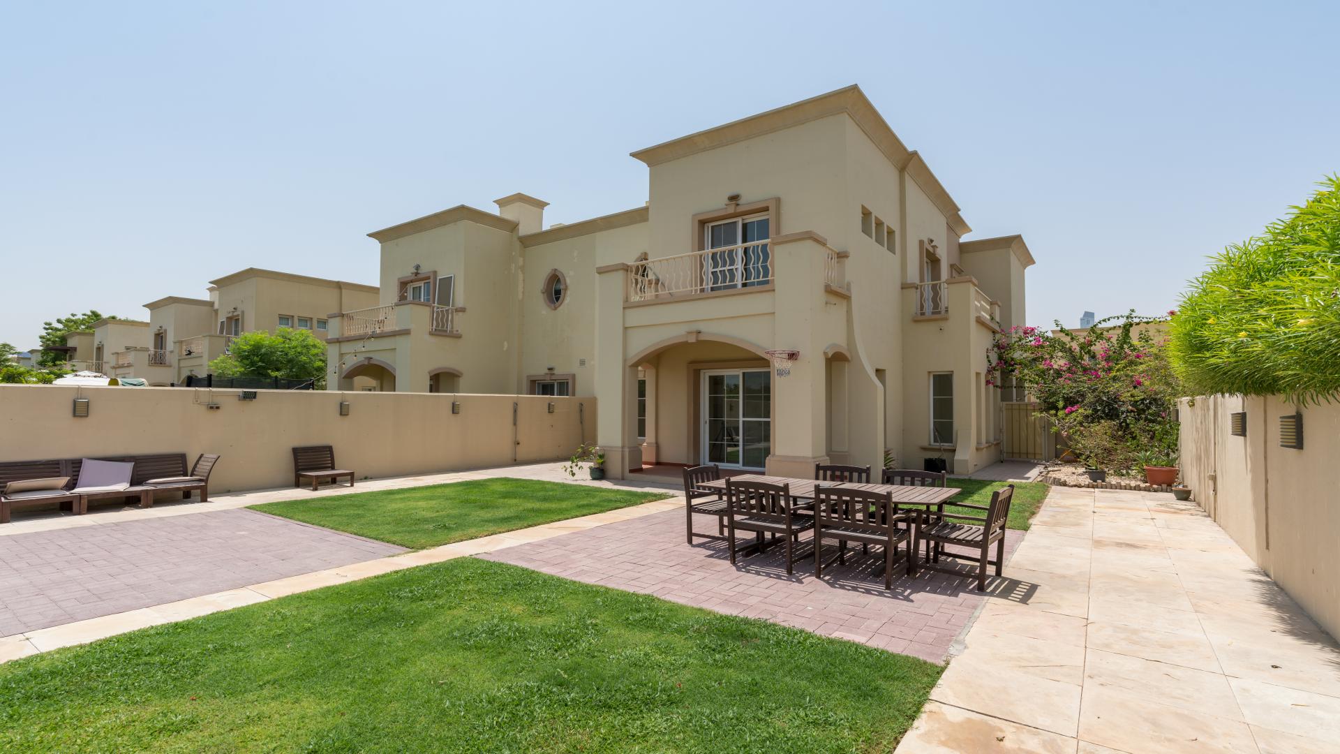 Lake-facing villa patio with outdoor dining set, lush garden, and basketball hoop in The Springs