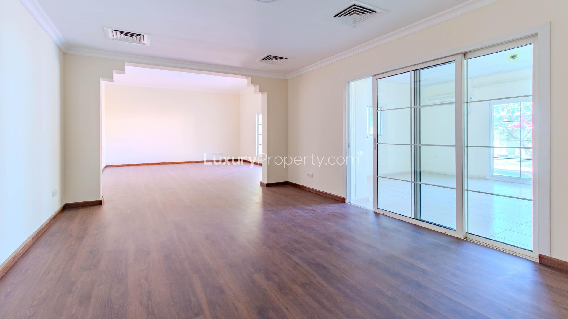 "Spacious living area in upgraded 3-bedroom villa, Meadows 1, with wooden flooring and large windows.",Empty living room in upgraded Meadows 1 villa, tiled floor, natural light, rental property