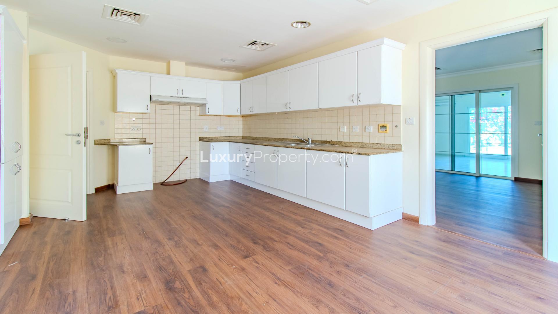 Upgraded kitchen in 3-bedroom villa for rent, Meadows 1, featuring wooden floors and white cabinets