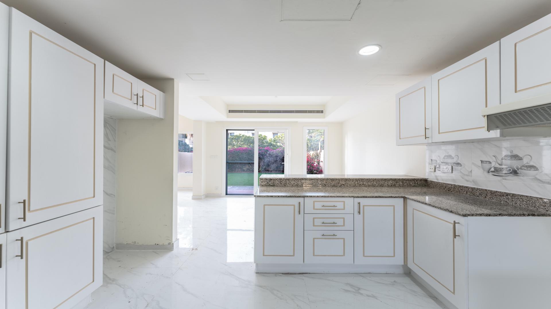 Modern kitchen with white cabinets, marble backsplash, and granite countertops in The Springs villa