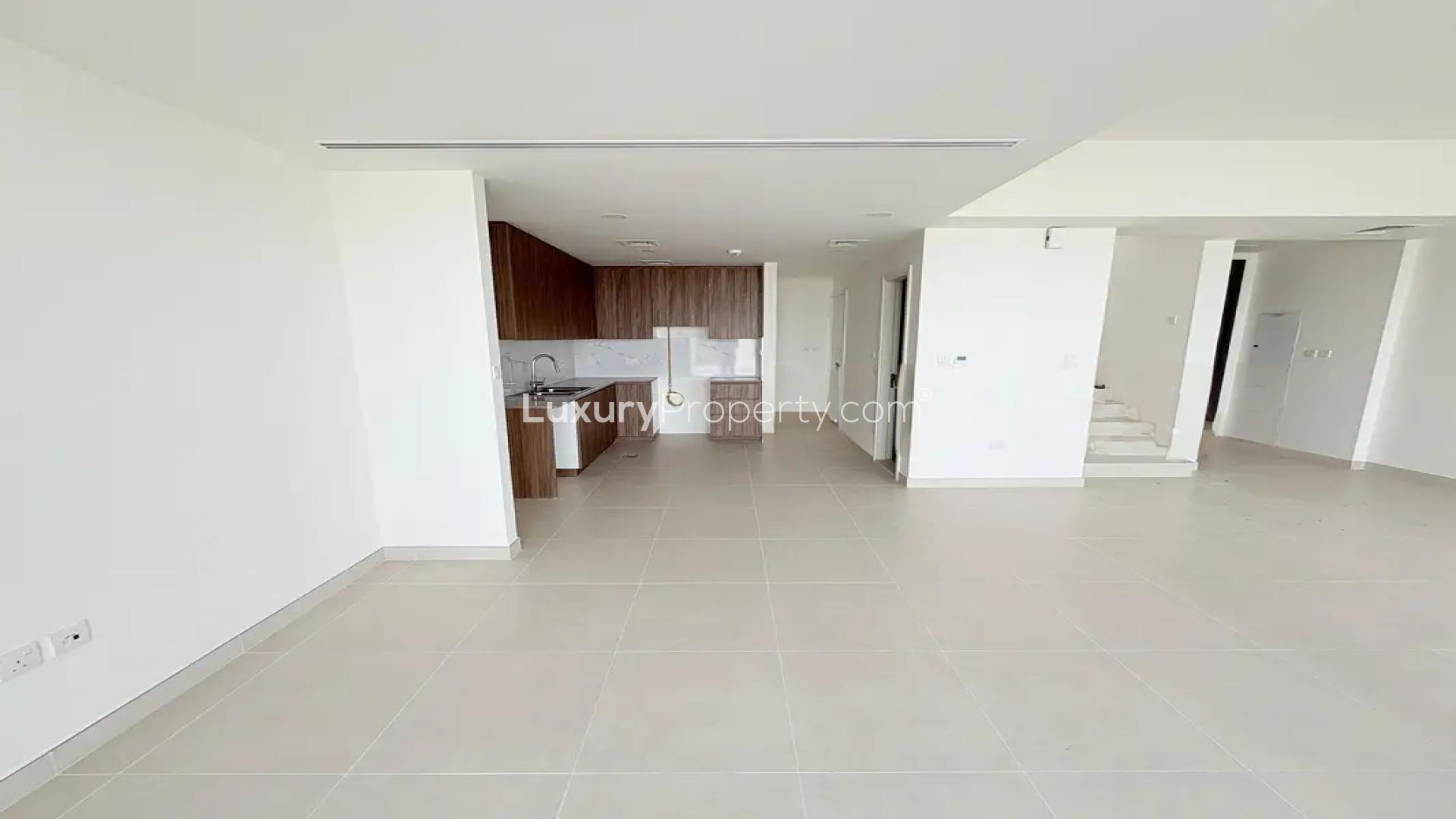 "Spacious backyard of rental villa in Maha Townhouses, Town Square, perfect for outdoor activities.",Modern open-plan kitchen and living area in Maha Townhouses villa, Town Square
