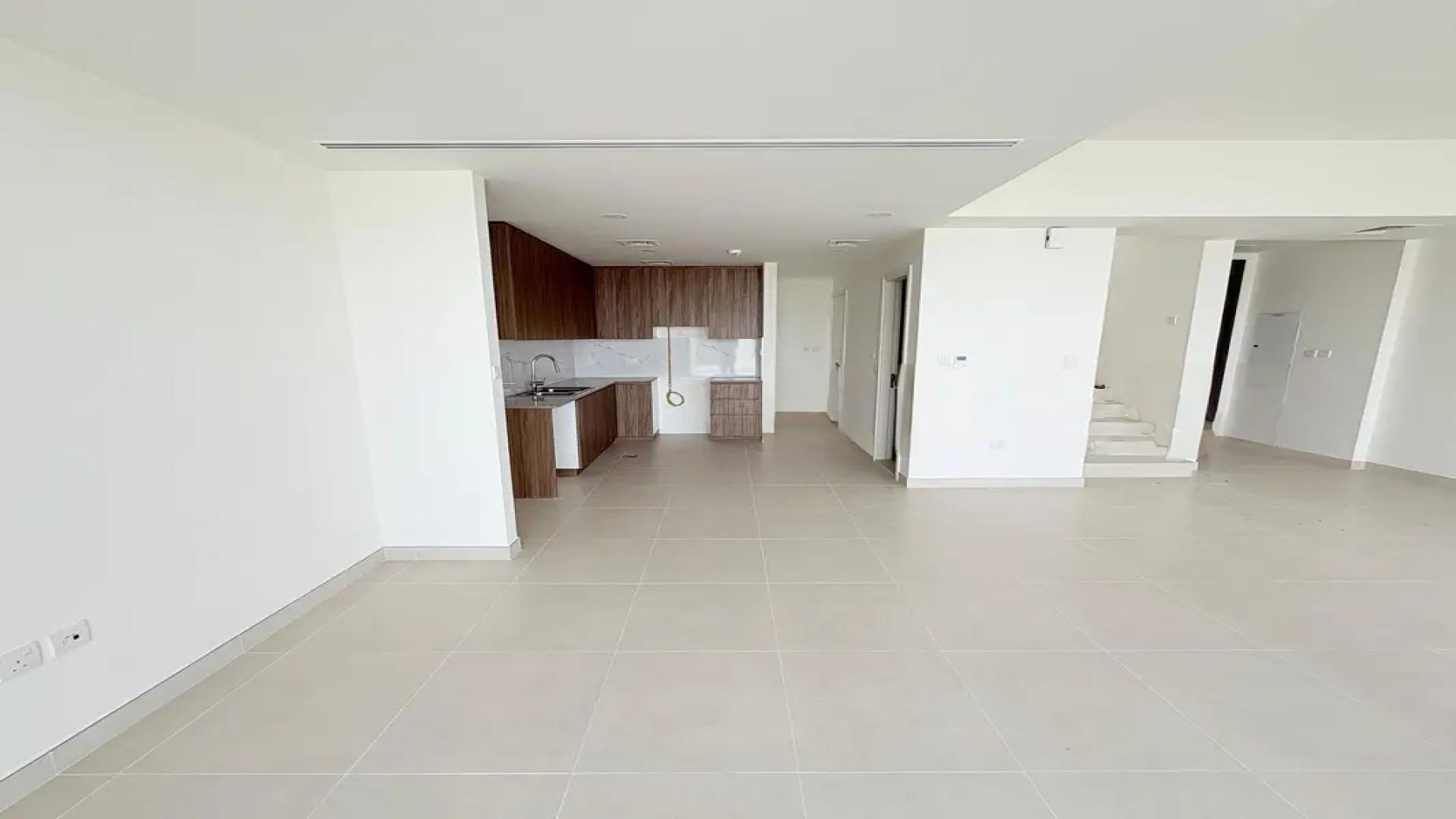 "Spacious backyard of rental villa in Maha Townhouses, Town Square, perfect for outdoor activities.",Modern open-plan kitchen and living area in Maha Townhouses villa, Town Square