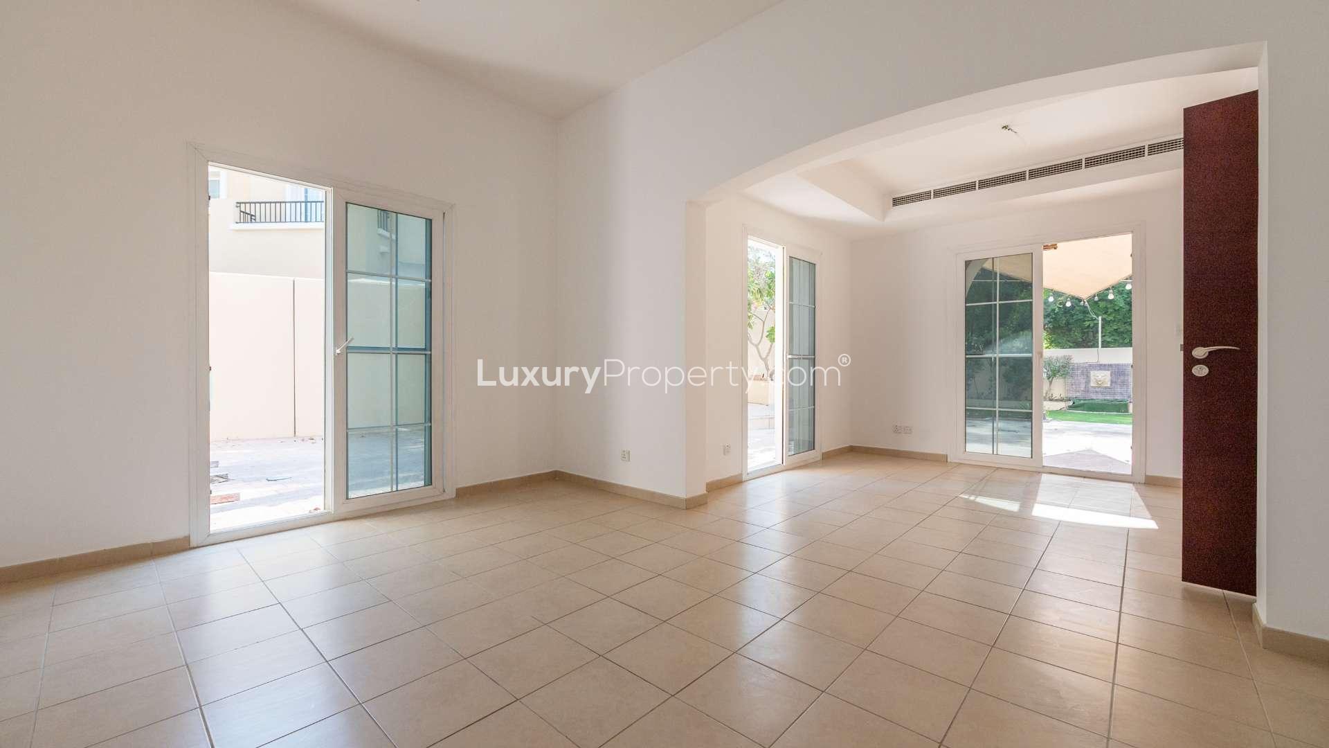 "Spacious living room with tiled flooring in Arabian Ranches Type 2E corner villa, Al Reem.",Bright living room in Type 2E villa, Al Reem, Arabian Ranches, with patio access