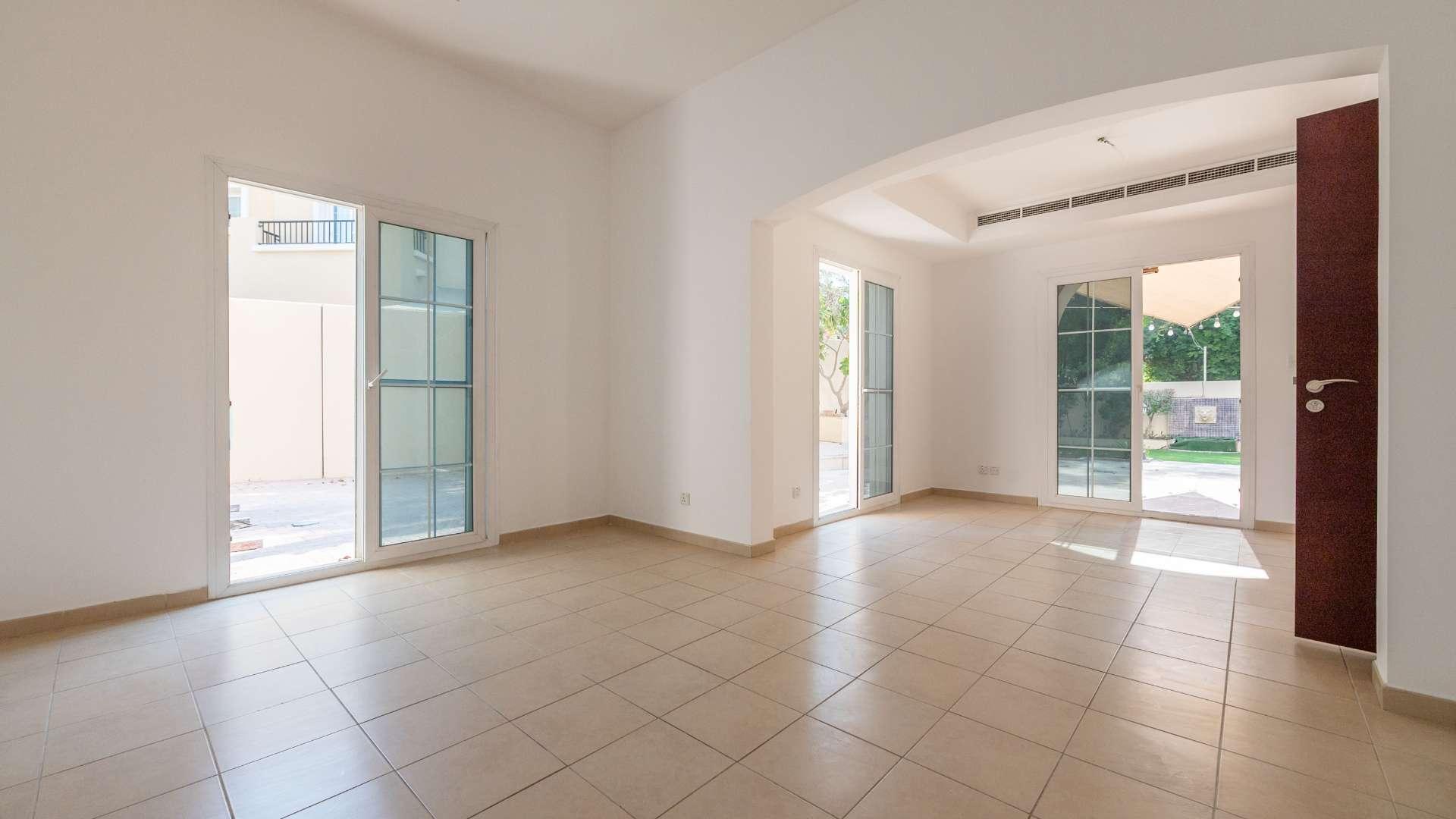 "Spacious living room with tiled flooring in Arabian Ranches Type 2E corner villa, Al Reem.",Bright living room in Type 2E villa, Al Reem, Arabian Ranches, with patio access