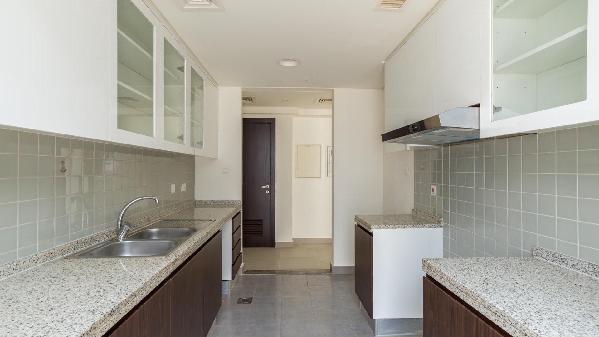 Entrance hall with wooden door and modern bathroom in Arabella Townhouses villa, Mudon