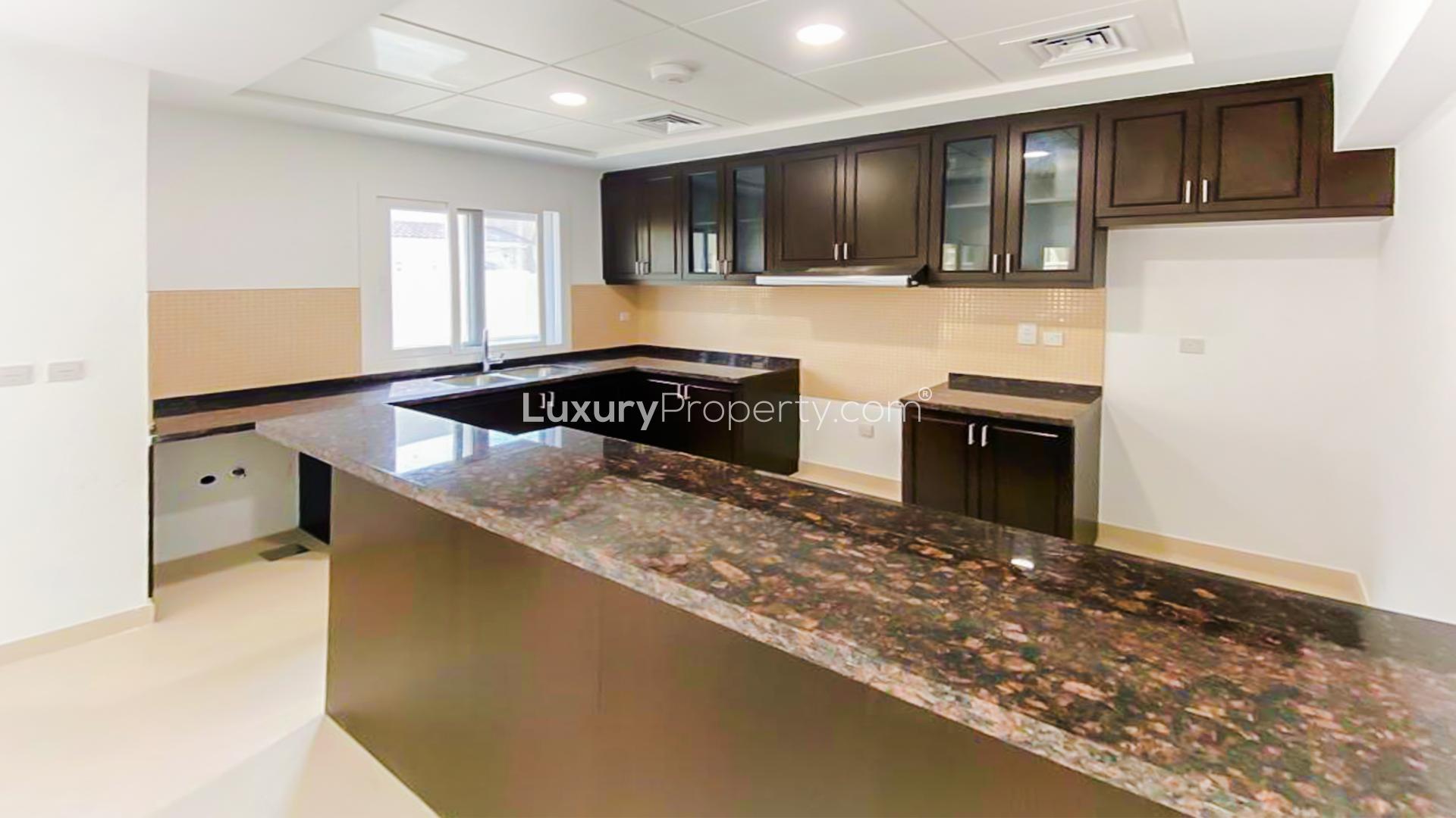 Modern kitchen in three-bedroom villa, Casa Viva, Serena, Dubai, featuring sleek dark cabinets