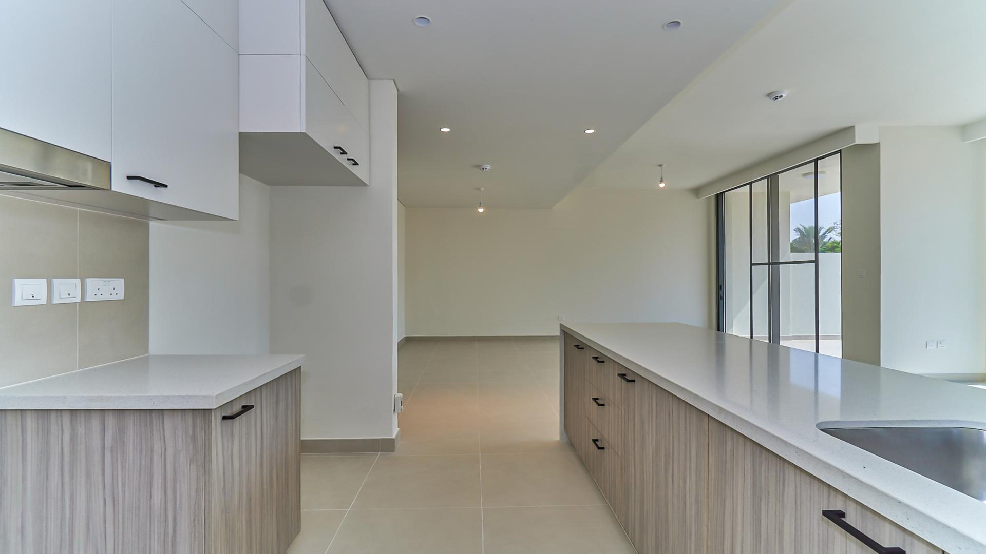 Outdoor pool area at Club Villas, Dubai Hills Estate, with palm trees and lounge chairs