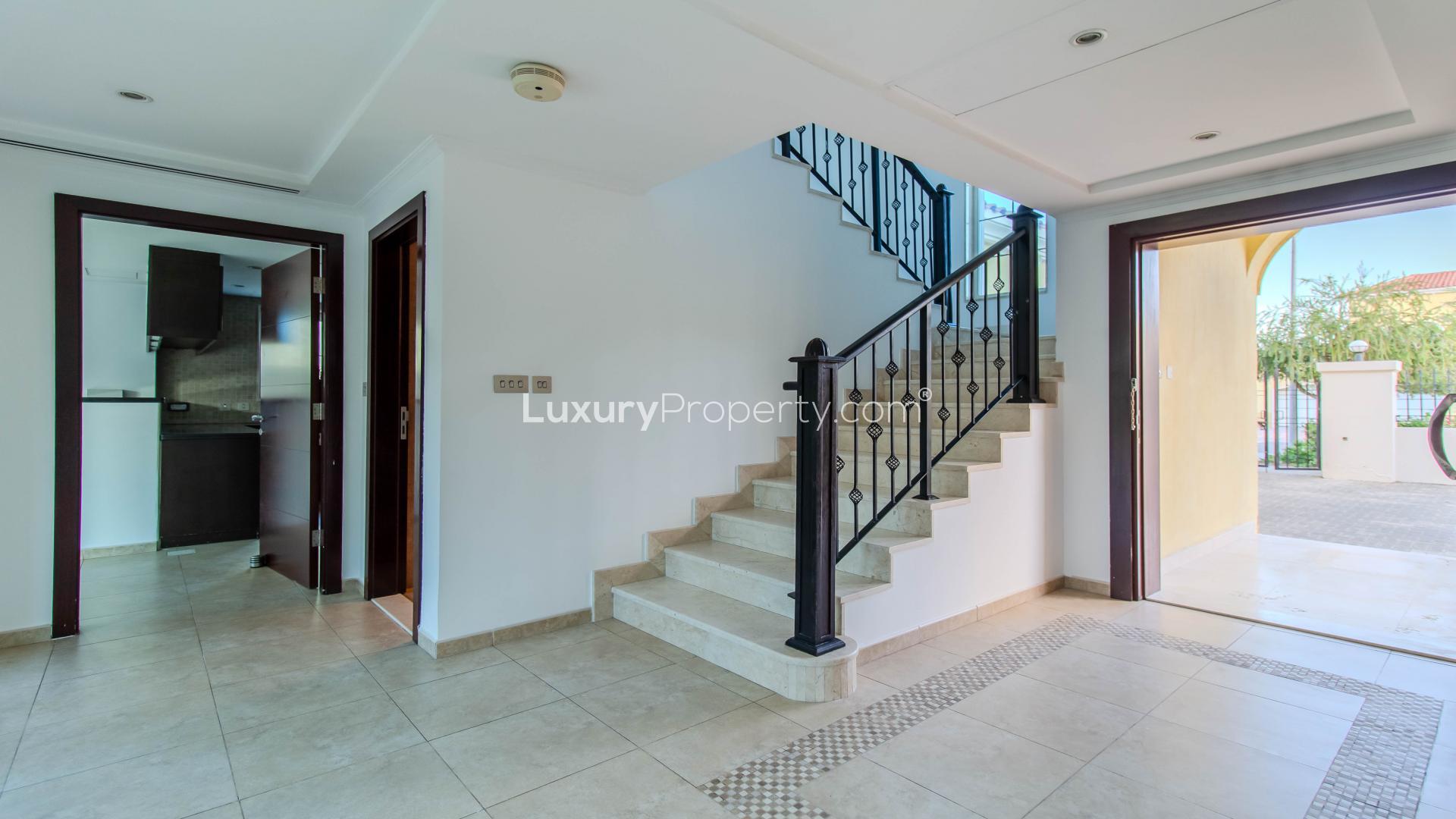 "Spacious 3-bedroom villa exterior in Jumeirah Park's Legacy community, lush garden view.",Elegant entrance of Jumeirah Park villa with staircase and open doorway in Legacy community