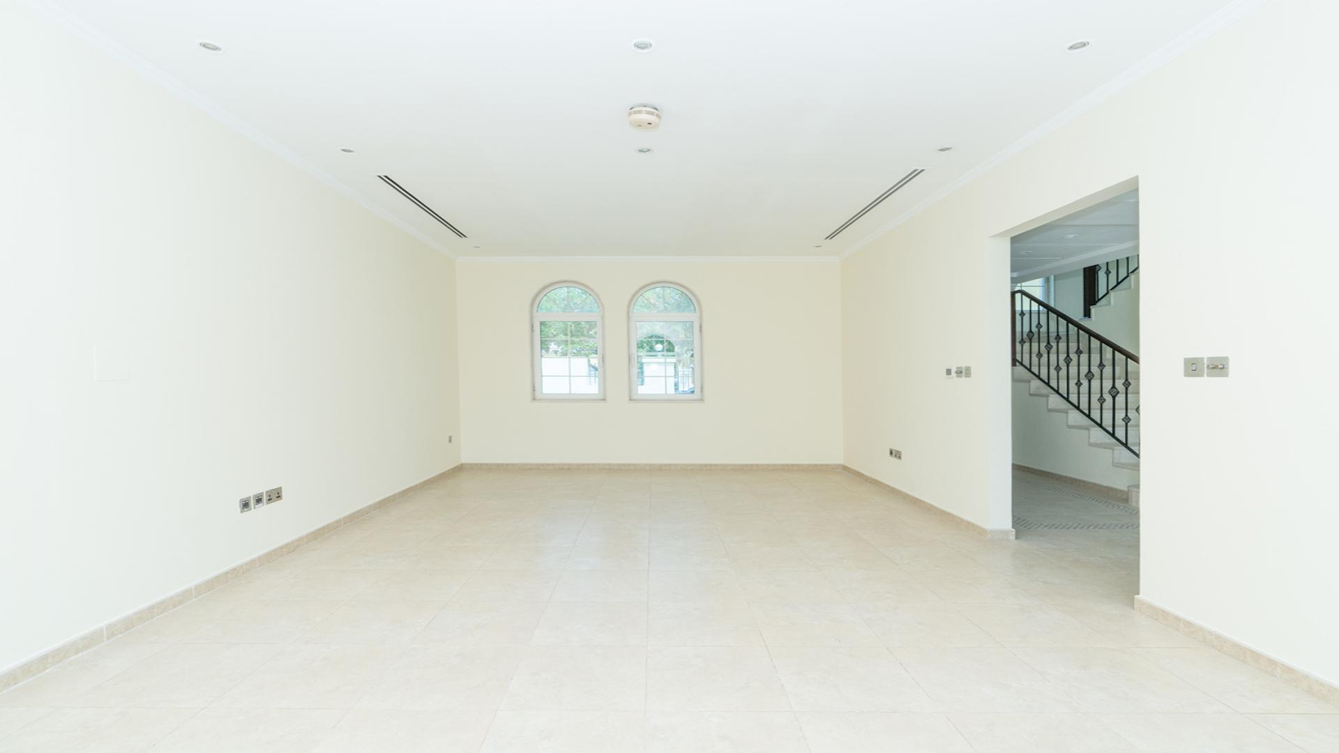 "Spacious living area with large windows in Jumeirah Park Legacy villa for rent.",Empty living room in Jumeirah Park villa with staircase and windows, Legacy sub-community