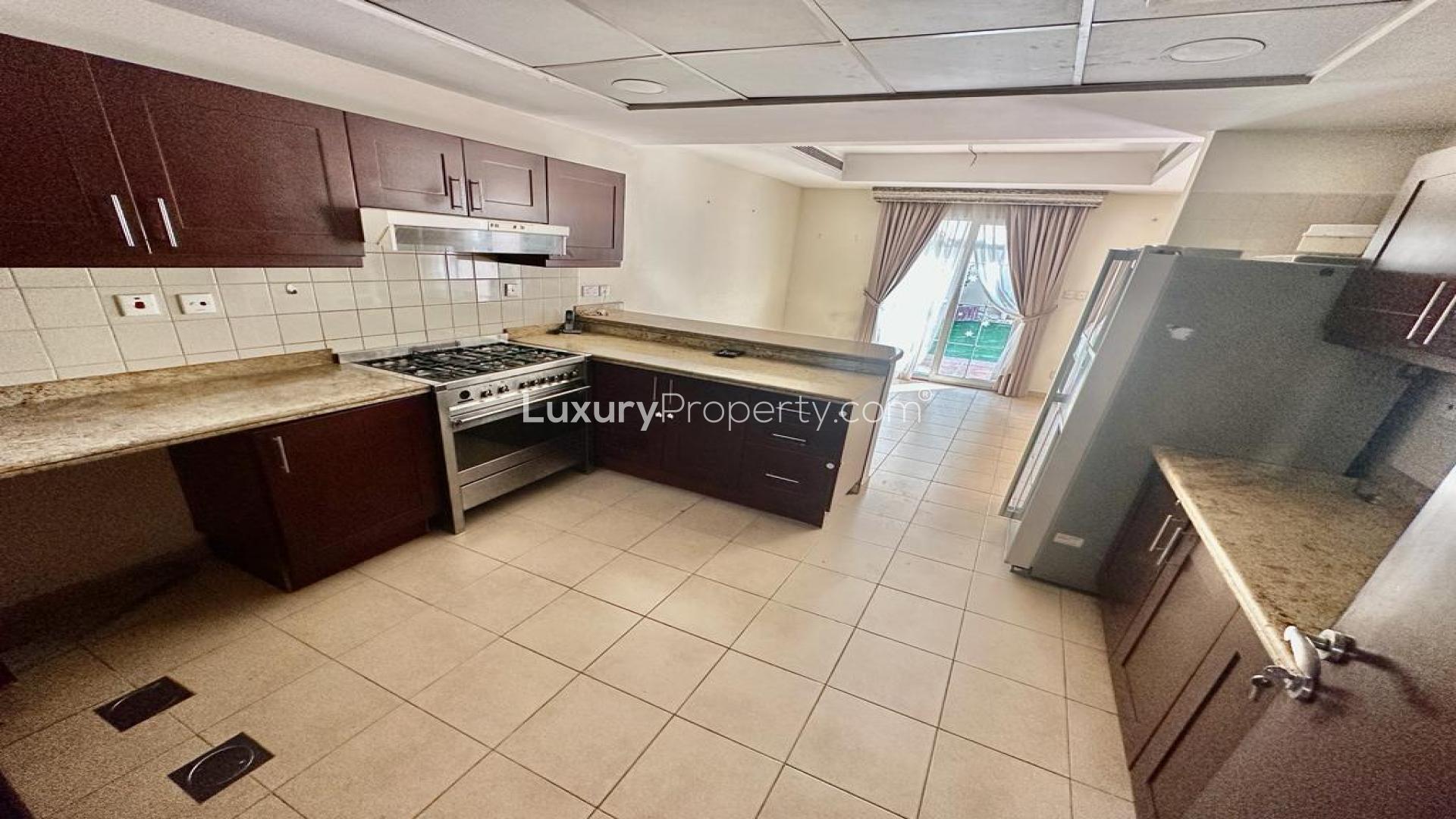 Spacious kitchen in vacant Al Reem villa, Arabian Ranches, with modern appliances and patio view