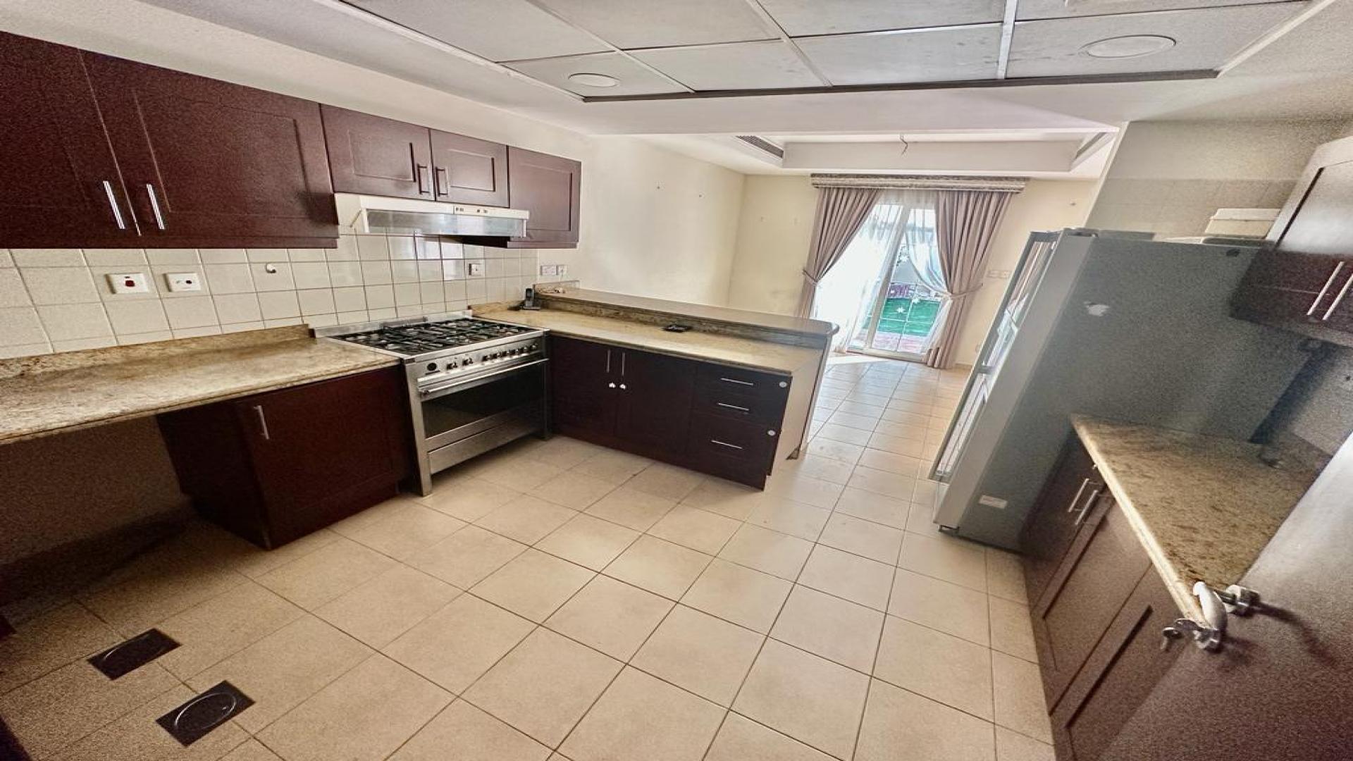 Spacious kitchen in vacant Al Reem villa, Arabian Ranches, with modern appliances and patio view