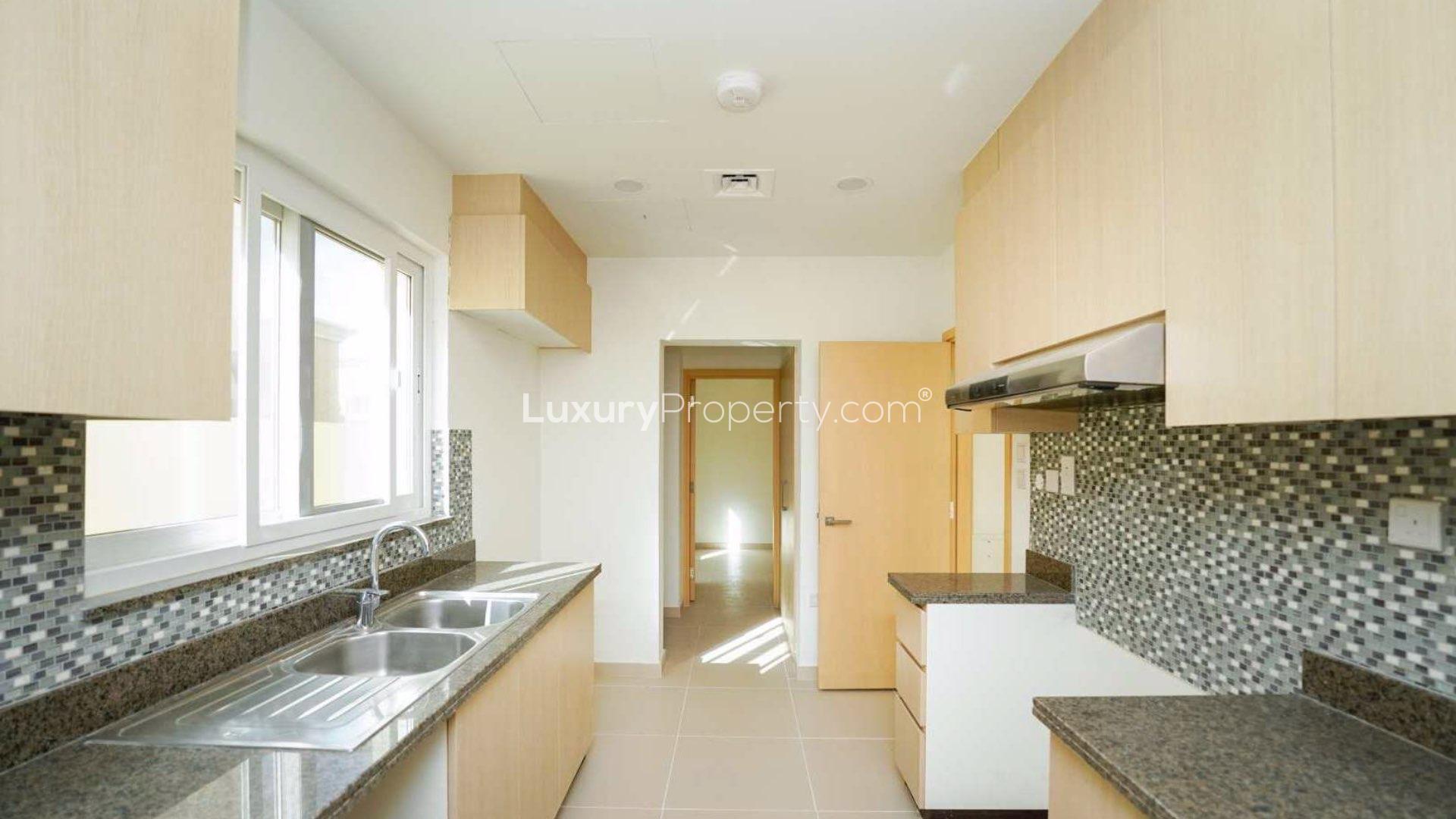 Modern kitchen in Villanova villa, Dubai Land, featuring sleek countertops and ample cabinetry