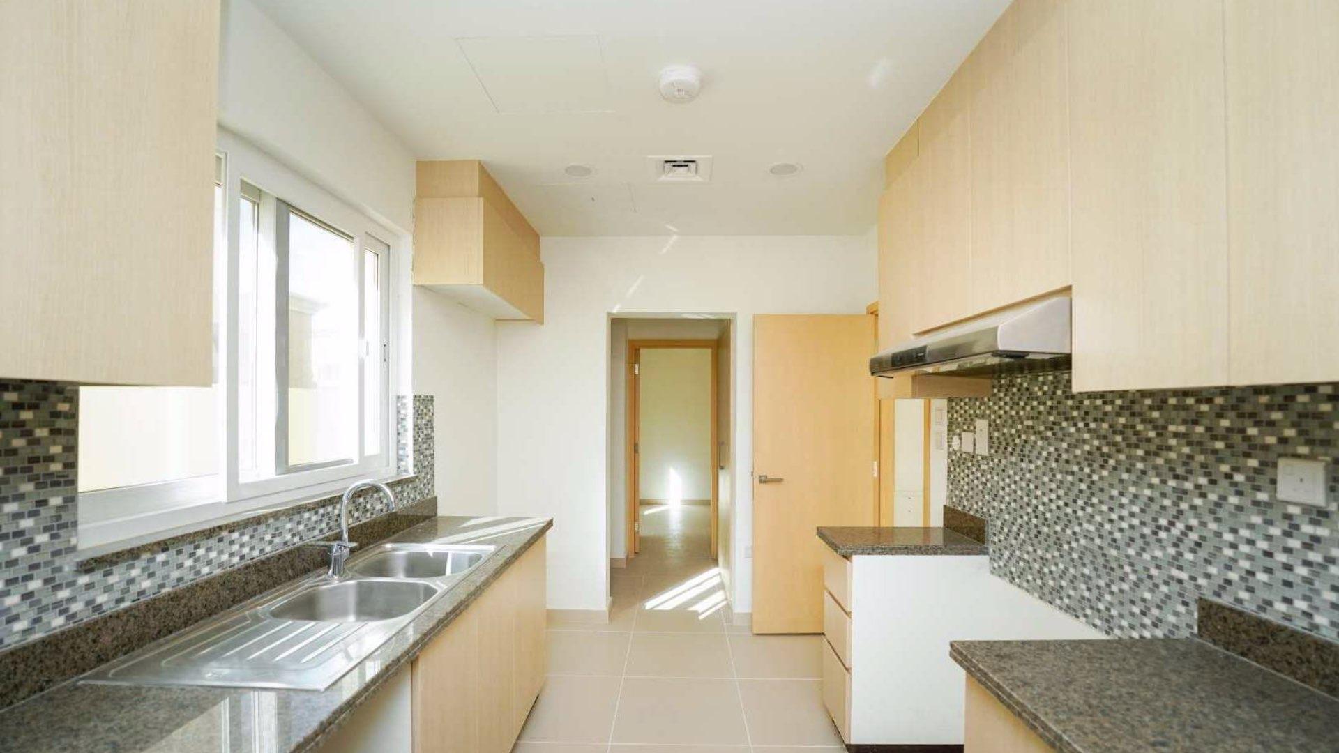 Modern kitchen in Villanova villa, Dubai Land, featuring sleek countertops and ample cabinetry