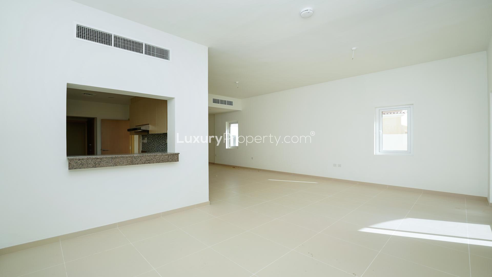 Spacious living room in Villanova villa, Dubai Land, with sliding glass doors and tiled floor