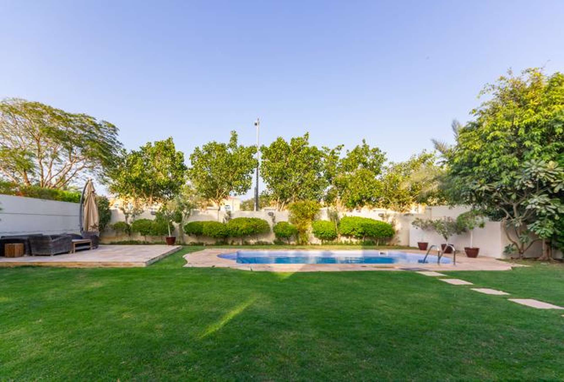 Spacious backyard with pool in Jumeirah Park villa for rent, lush greenery surrounds