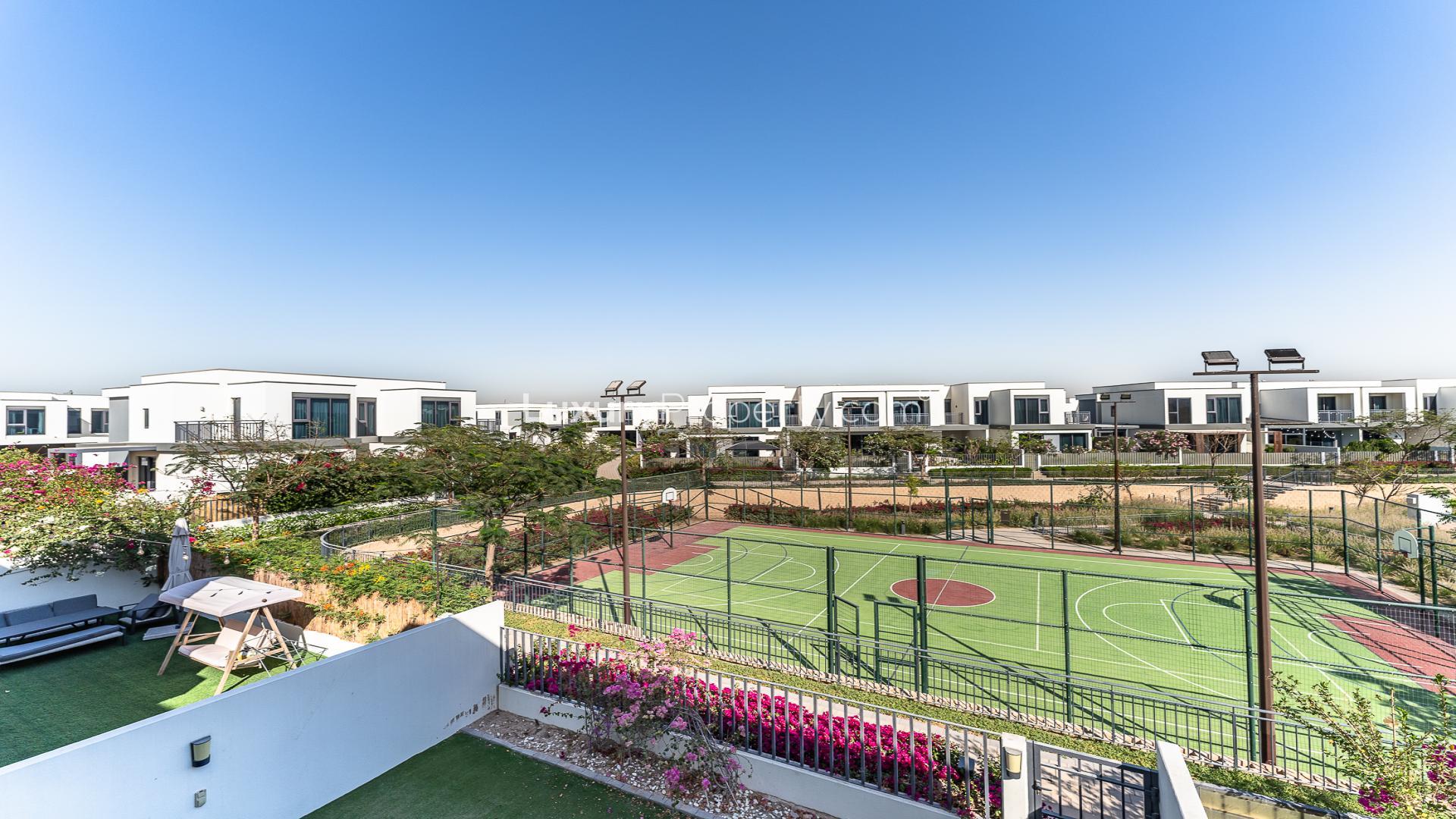 "Spacious backyard of family-friendly villa in Maple, Dubai Hills Estate, for rent.",Villa with garden view over sports court in Dubai Hills Estate, Maple community