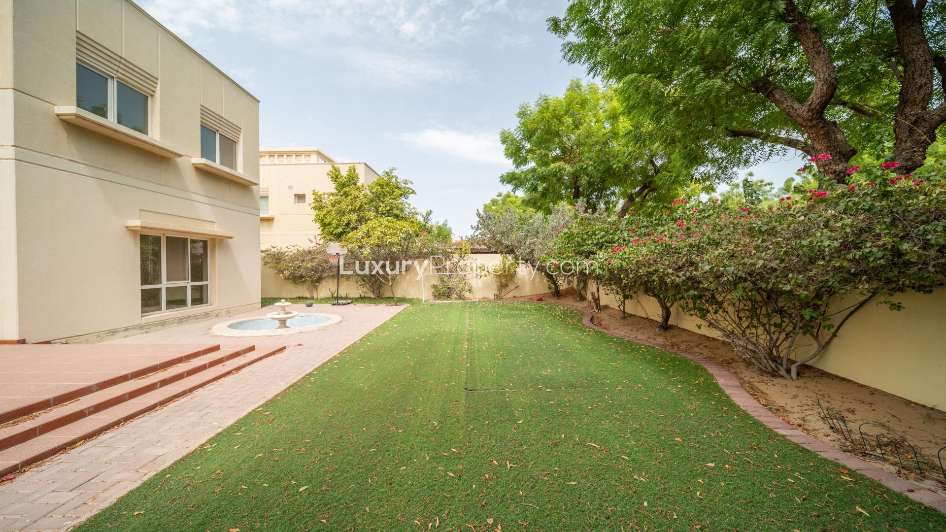 Backyard view of Meadows 9 villa with green lawn and trees, available for rent