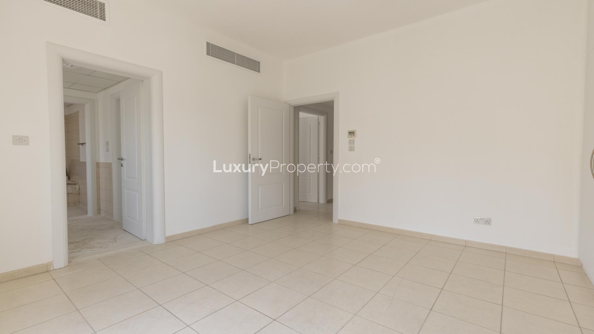 "Spacious interior of three-bedroom villa in Meadows 6 with tiled floors and white walls.","Spacious bedroom with built-in wardrobes in Meadows 6 villa for rent, bright and airy.",Empty living room in three-bedroom villa, Meadows 6, with tiled floor and large windows