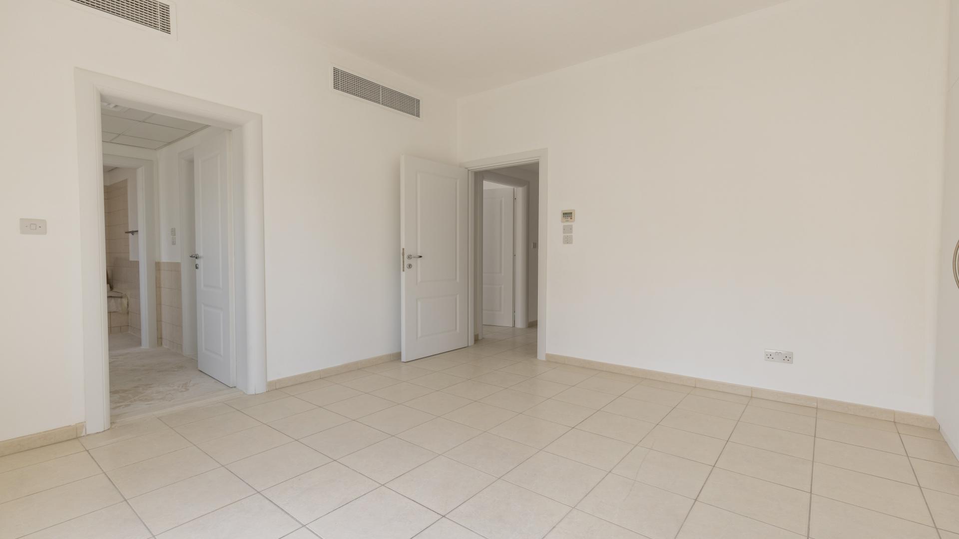 "Spacious interior of three-bedroom villa in Meadows 6 with tiled floors and white walls.","Spacious bedroom with built-in wardrobes in Meadows 6 villa for rent, bright and airy.",Empty living room in three-bedroom villa, Meadows 6, with tiled floor and large windows