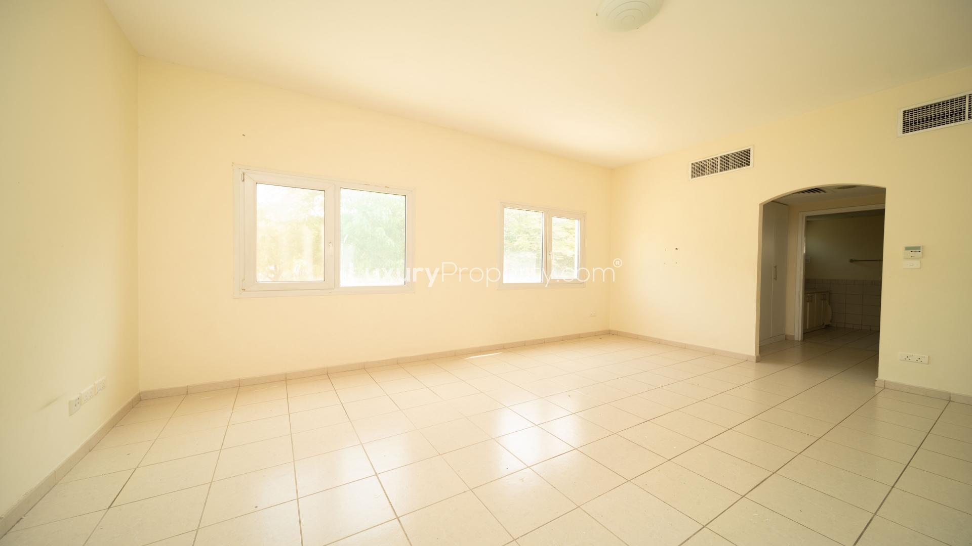 Empty room in three-bedroom villa, Meadows 6, with tiled floors and large windows